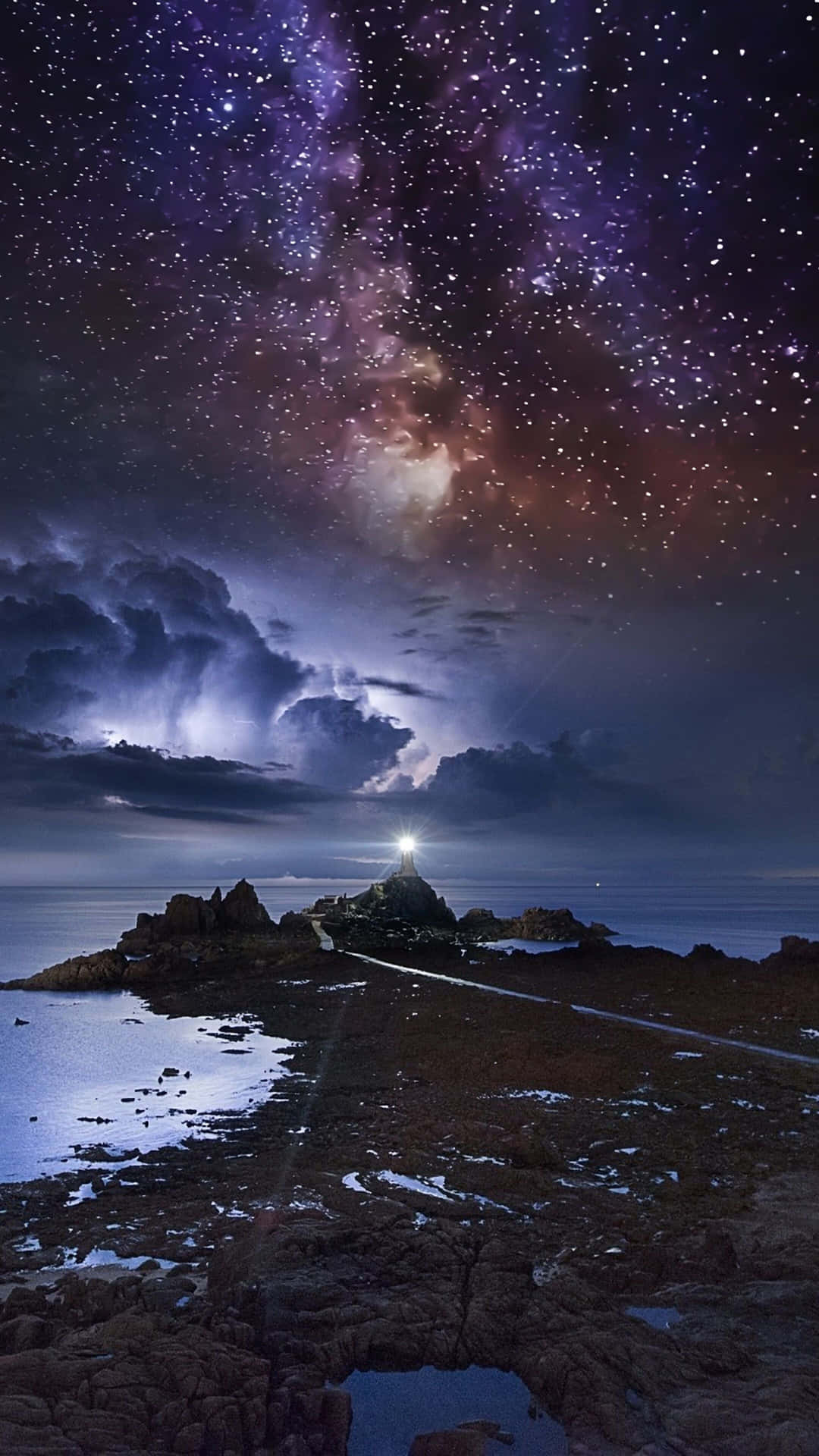 燈塔在岩石海岸上發光，星空下