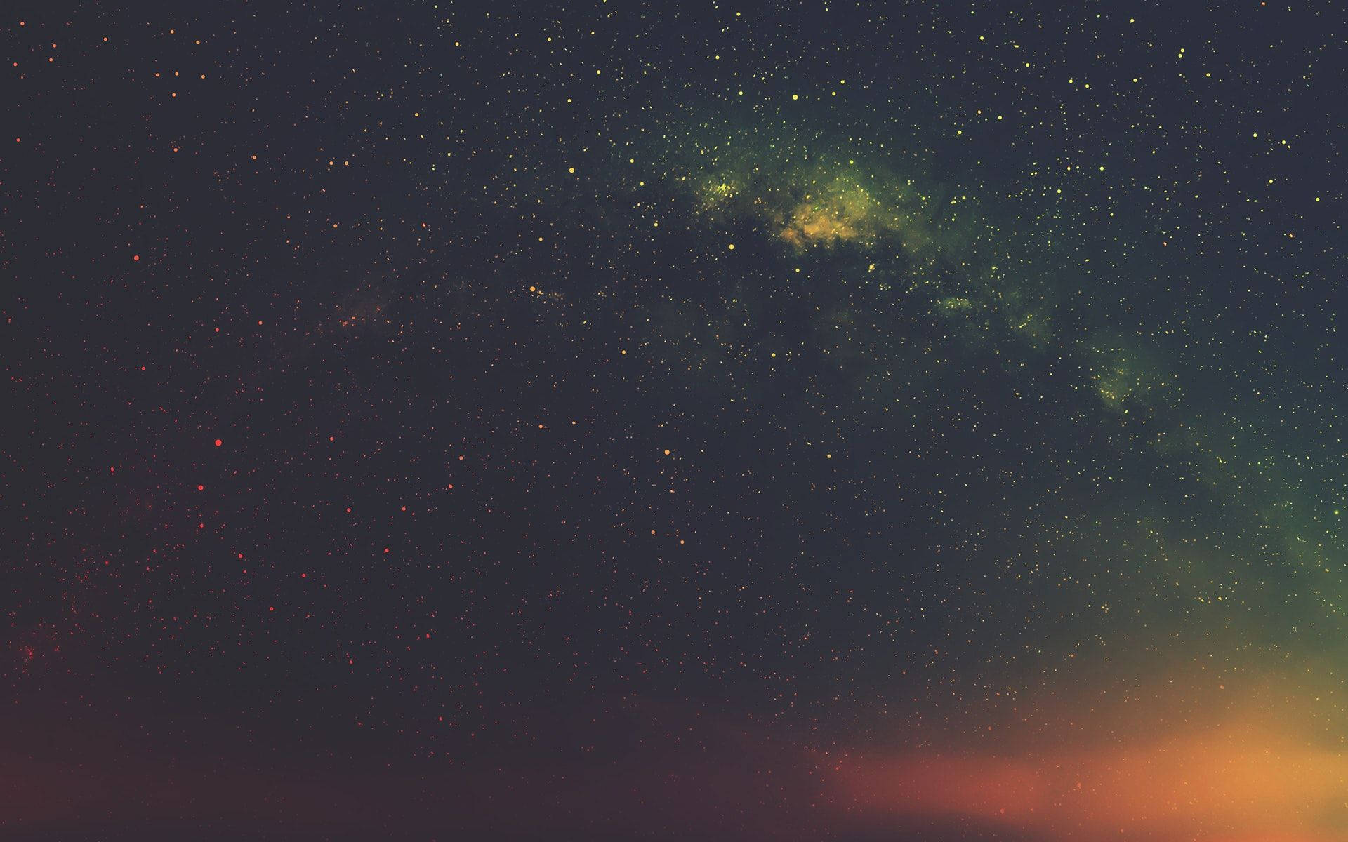 廣闊的夜空，星星和彩色星雲在地平線上方發光。
