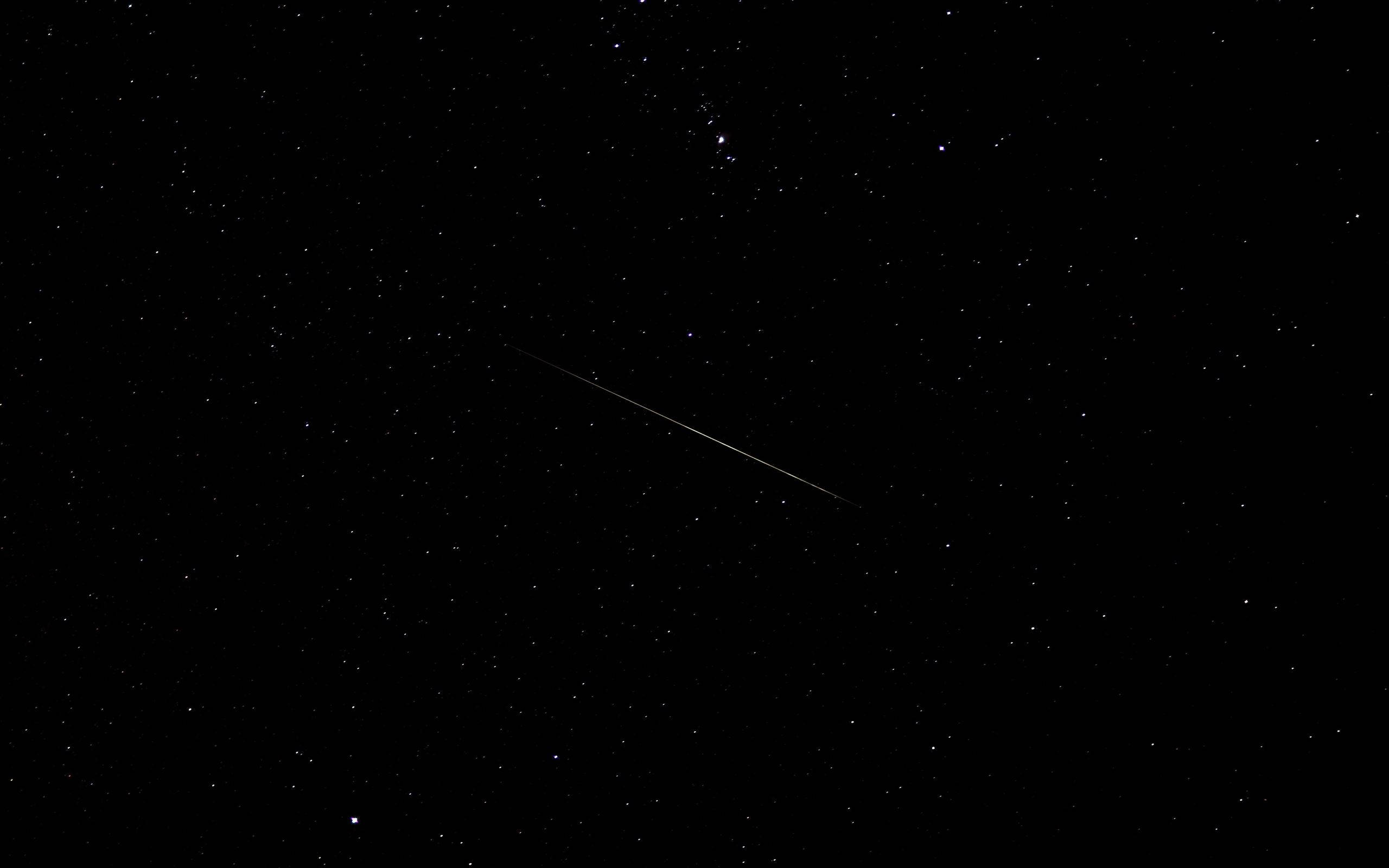 星系星辰 macOS 壁紙 — 一顆明亮的流星斜斜地劃過佈滿星星的黑色夜空。