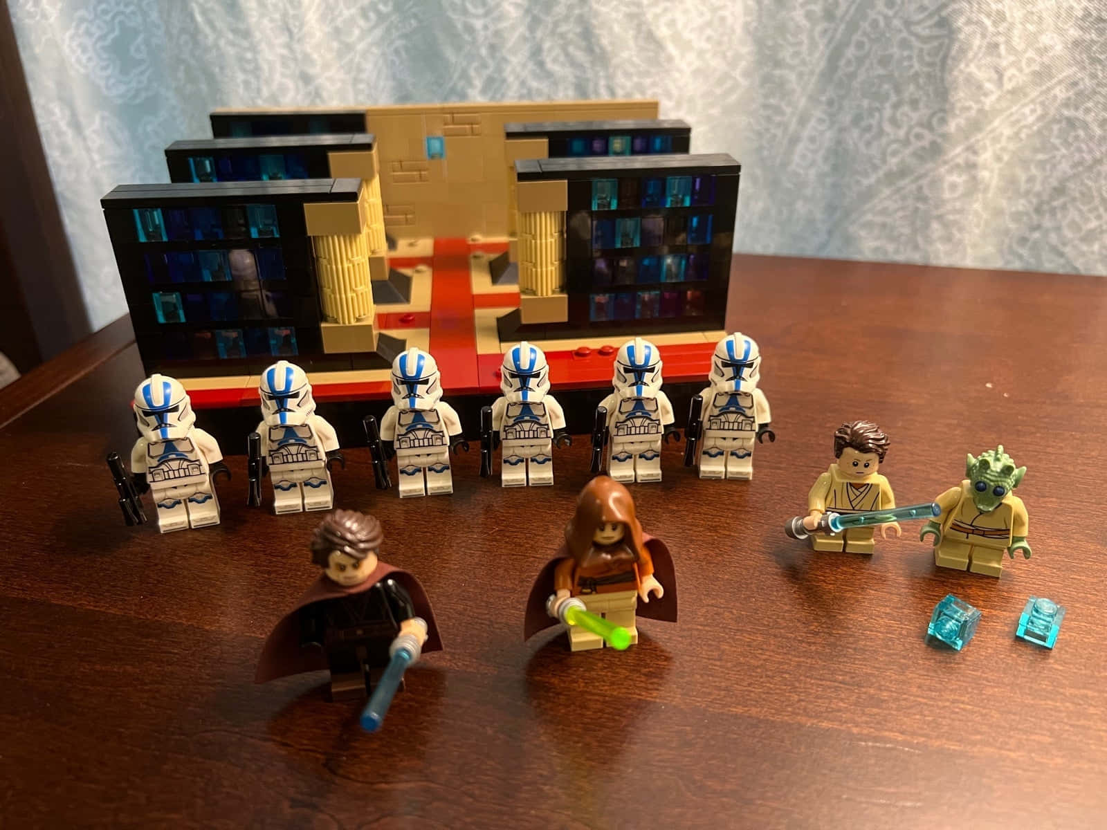The Order 66 桌布 壁紙 — 星際大戰 LEGO 人仔，包括複製人軍團和絕地武士，擺放在木桌上，前面有一個精細的 LEGO 建築。