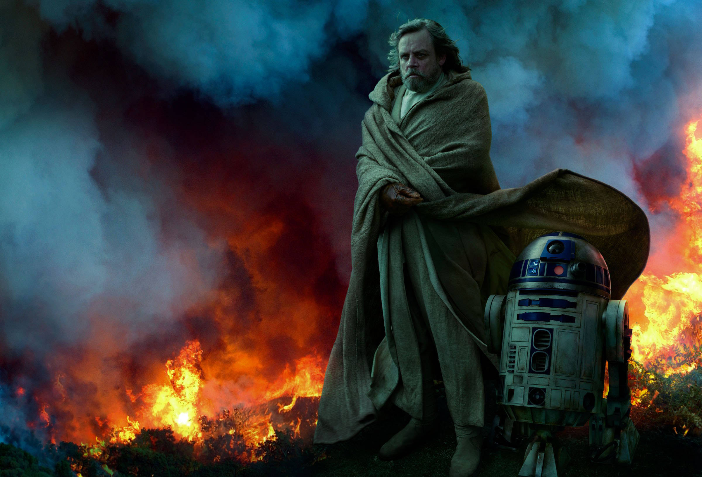 《星際大戰：天行者的崛起》路克與R2-D2 壁紙 — Luke Skywalker 莊嚴地站在 R2-D2 旁邊，身後火焰在煙霧瀰漫的黃昏天空下肆虐。