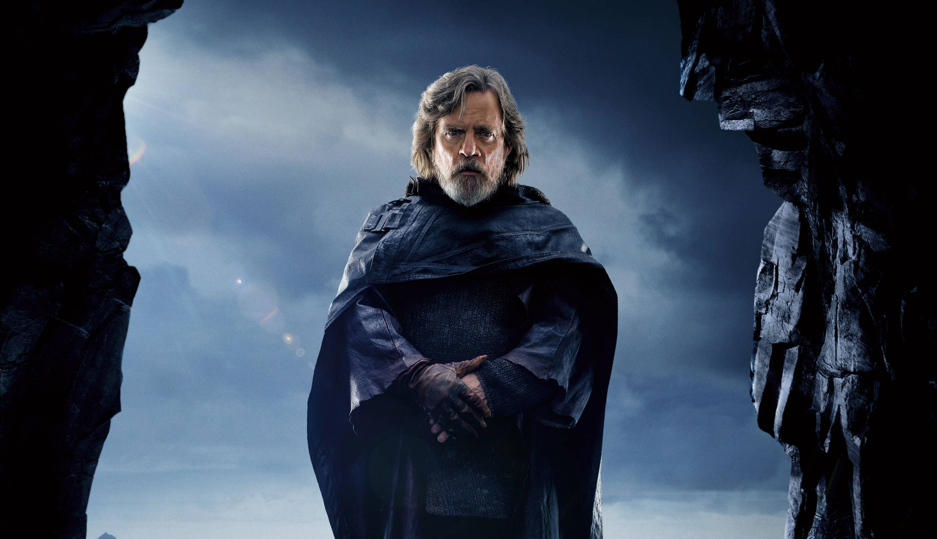 Luke Skywalker 身穿深色長袍，站在暴風雨天空下的岩石拱門中。