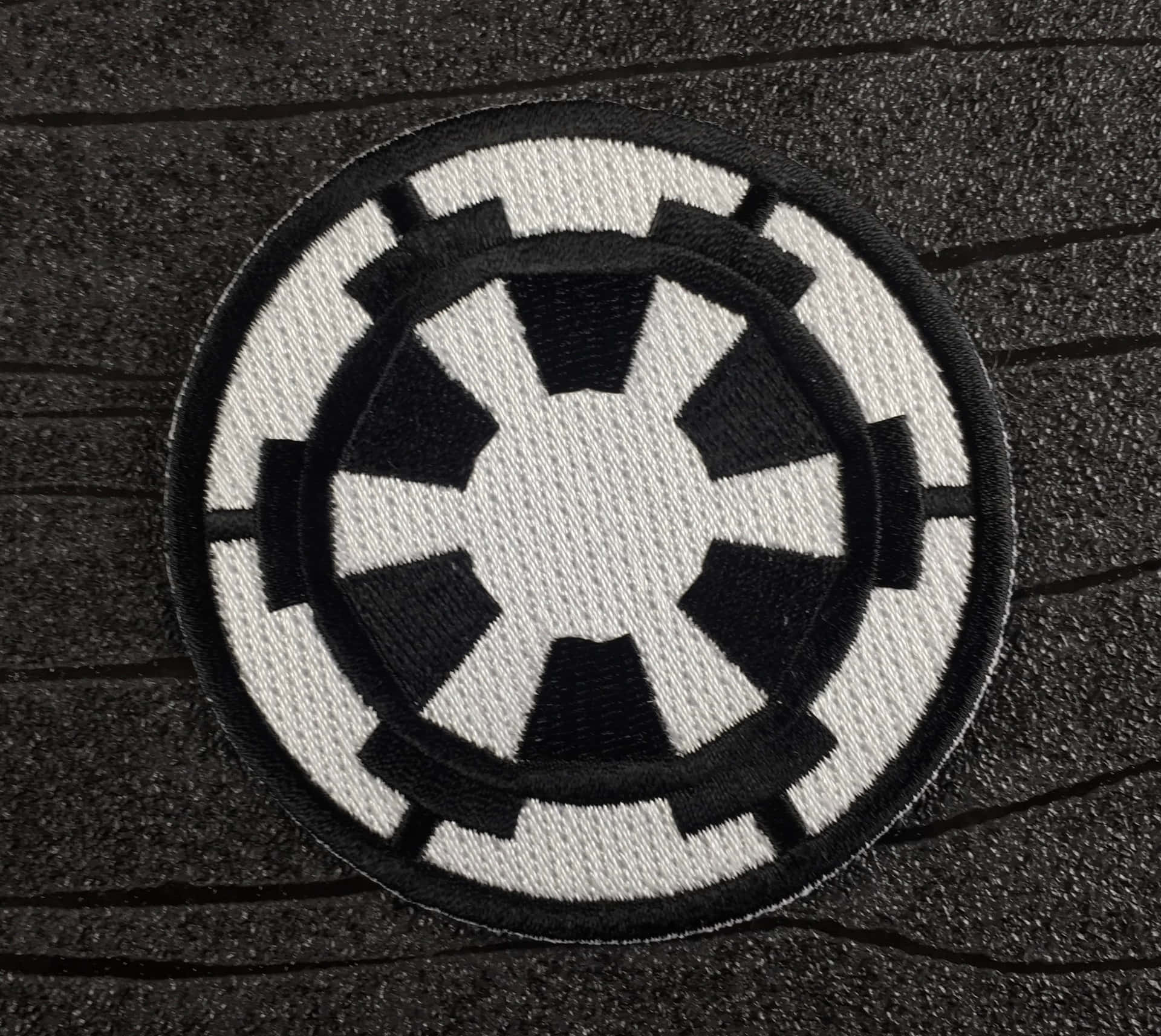 黑色和白色刺繡的帝國徽章補丁在深色紋理背景上。