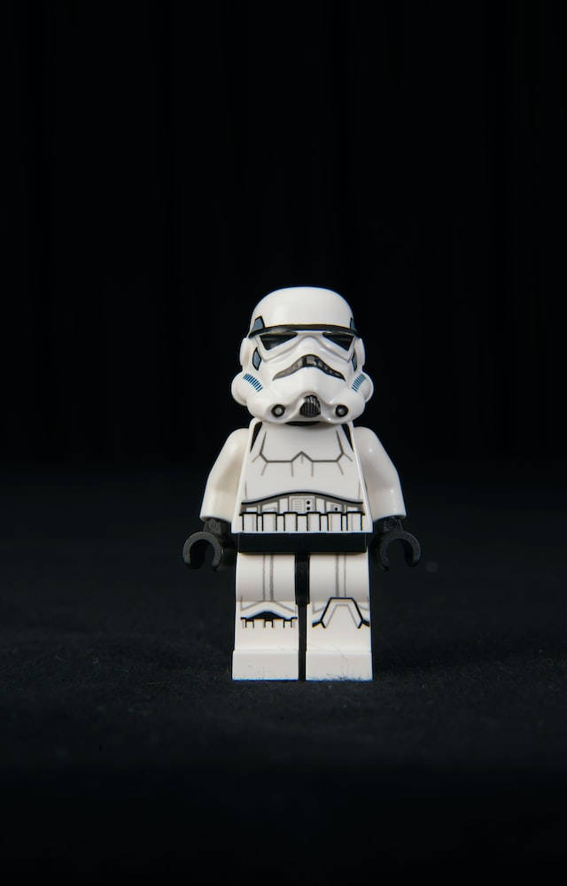 星際大戰經典戰鬥場景iPhone壁紙 壁紙 — 一個白色的LEGO風暴兵人偶在強烈黑色背景和戲劇性燈光下居中站立。
