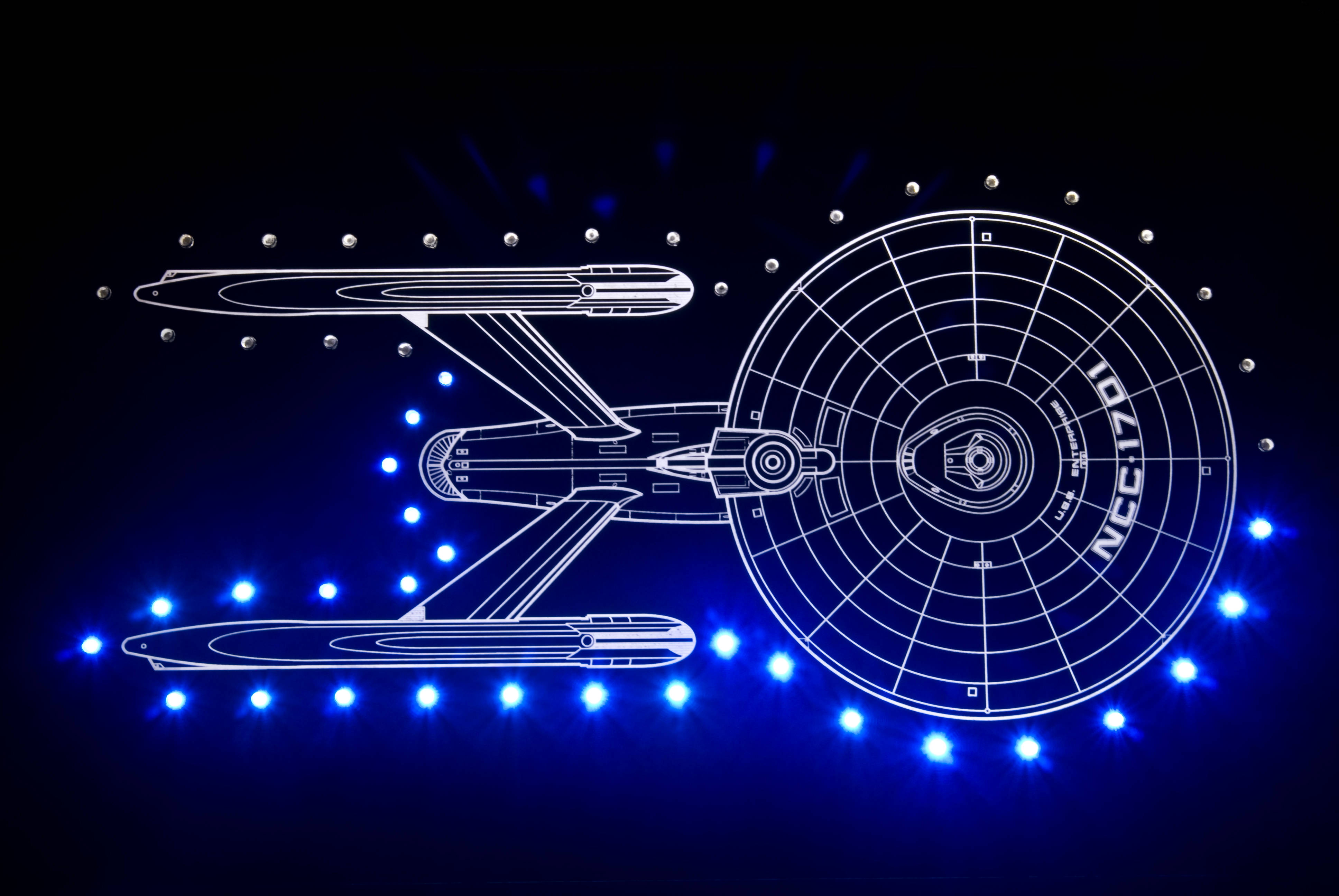 《星際迷航》iPhone 星艦藝術壁紙 壁紙 — 發光藍色輪廓的星艦企業號NCC-1701，背景為深色，帶有散落的光點。