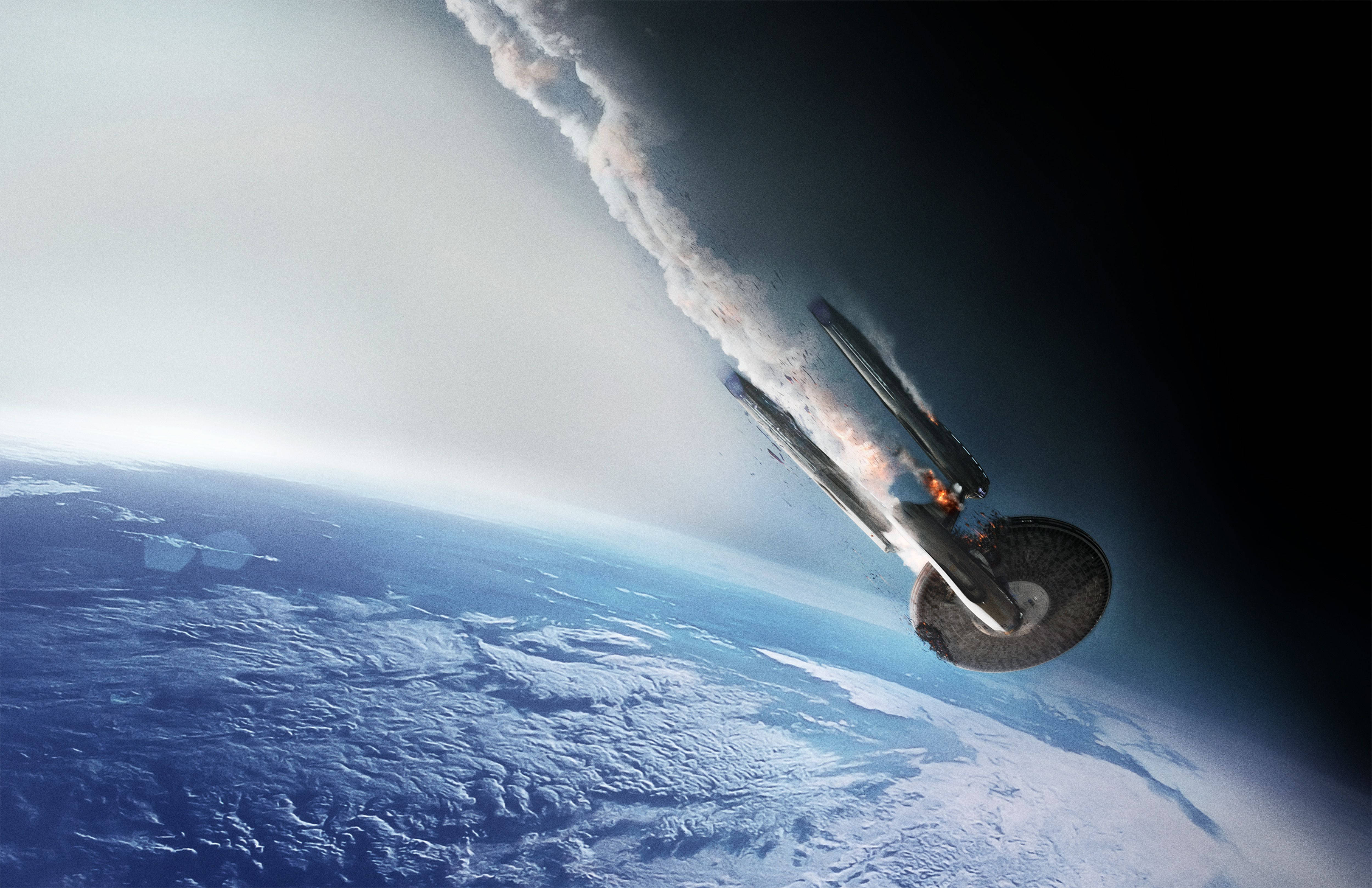 星際迷航：暗黑無垠墜毀飛船 壁紙 — 一艘受損的太空船劃過太空，在地球藍白雲層覆蓋的表面上方留下一道熾熱的痕跡。