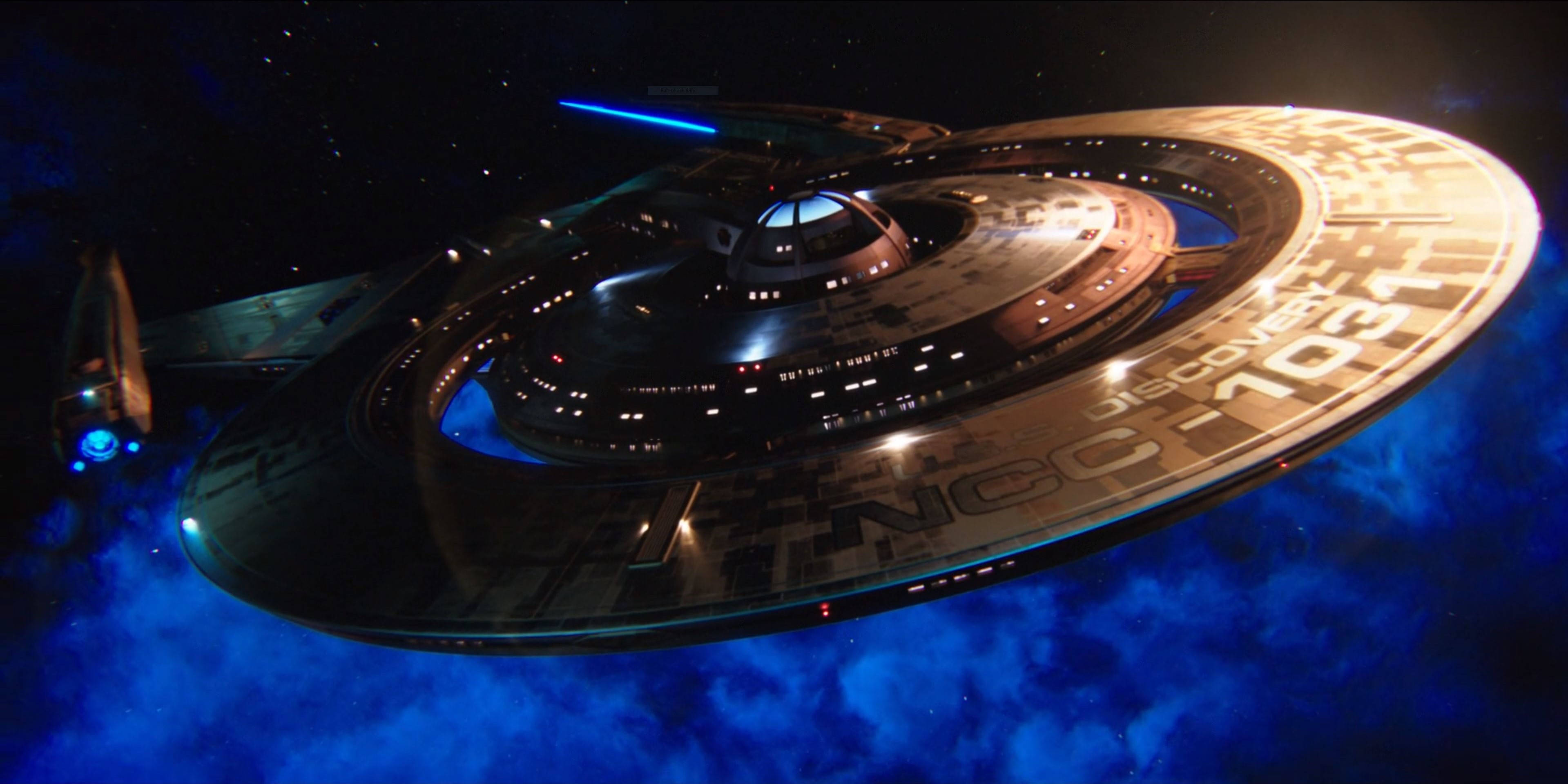 《星際迷航：發現號》星艦 壁紙 — USS Enterprise NCC-1701 在充滿活力的藍色星雲中滑行，星星在宇宙虛空中閃爍。
