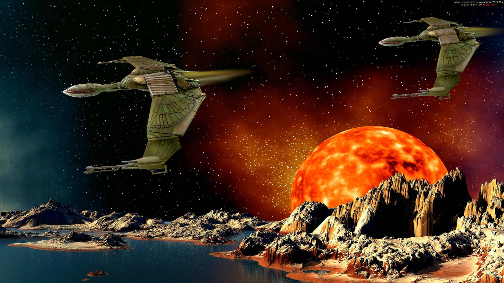 星際迷航星艦 克林貢星艦於行星上空 壁紙 — 兩艘未來主義的有翼太空船在一個岩石外星行星上空翱翔，一顆巨大的火橙色太陽在鋸齒狀山峰後升起。