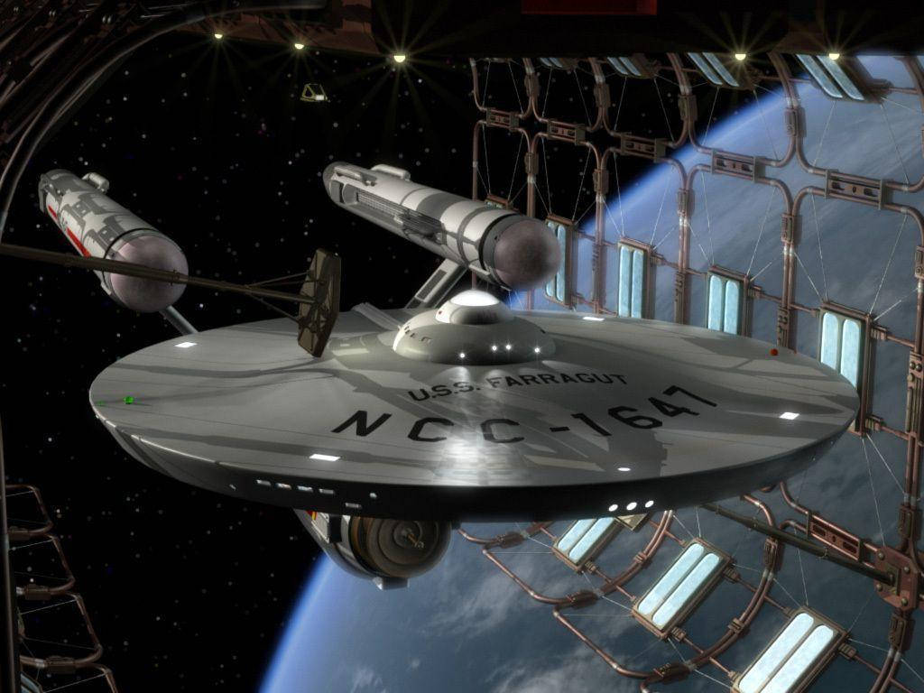 星際迷航法拉格特號星艦停泊於機庫 壁紙 — 一艘名為 U.S.S. Farragut NCC-1647 的銀色星艦停靠在太空站內，背景可見地球。