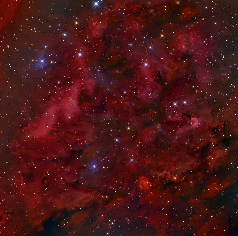 一個紅色和紫色的星雲，充滿了深空中的明亮星星。