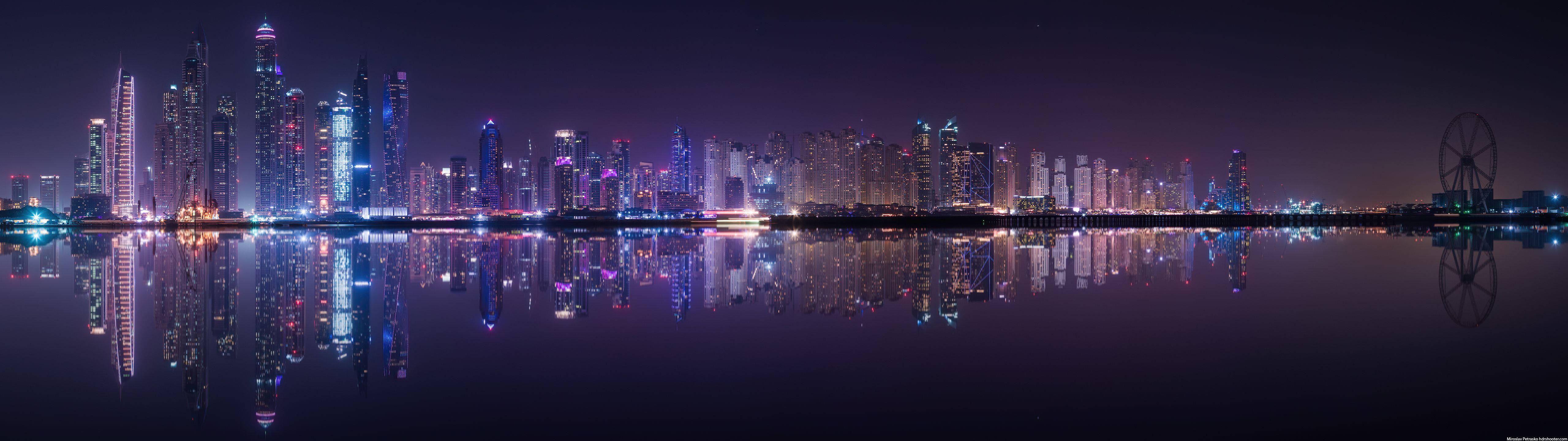 夜晚的杜拜天際線，摩天大樓和摩天輪倒映在水中。