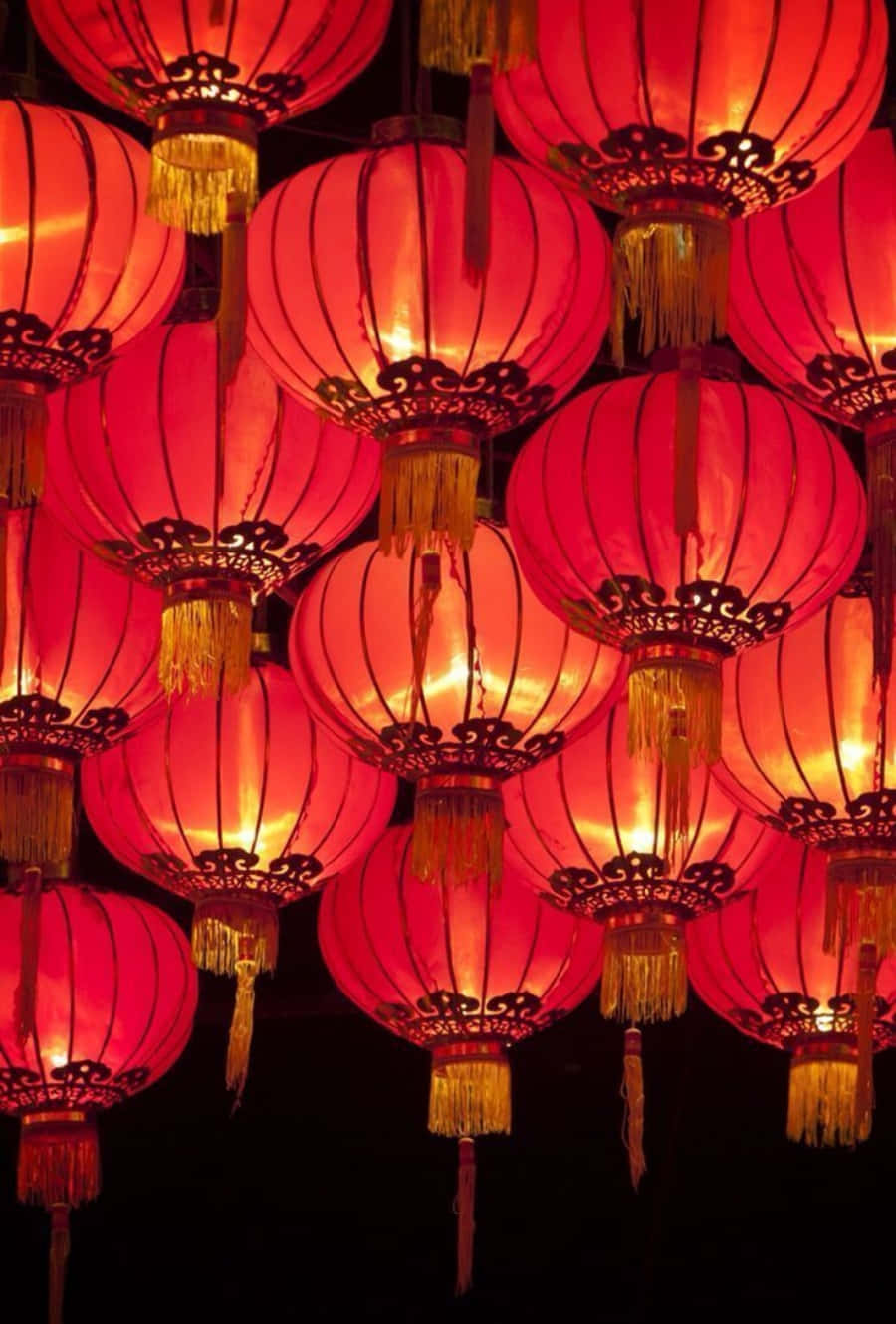夜間懸掛的一簇帶有金色流蘇的發光紅色燈籠。
