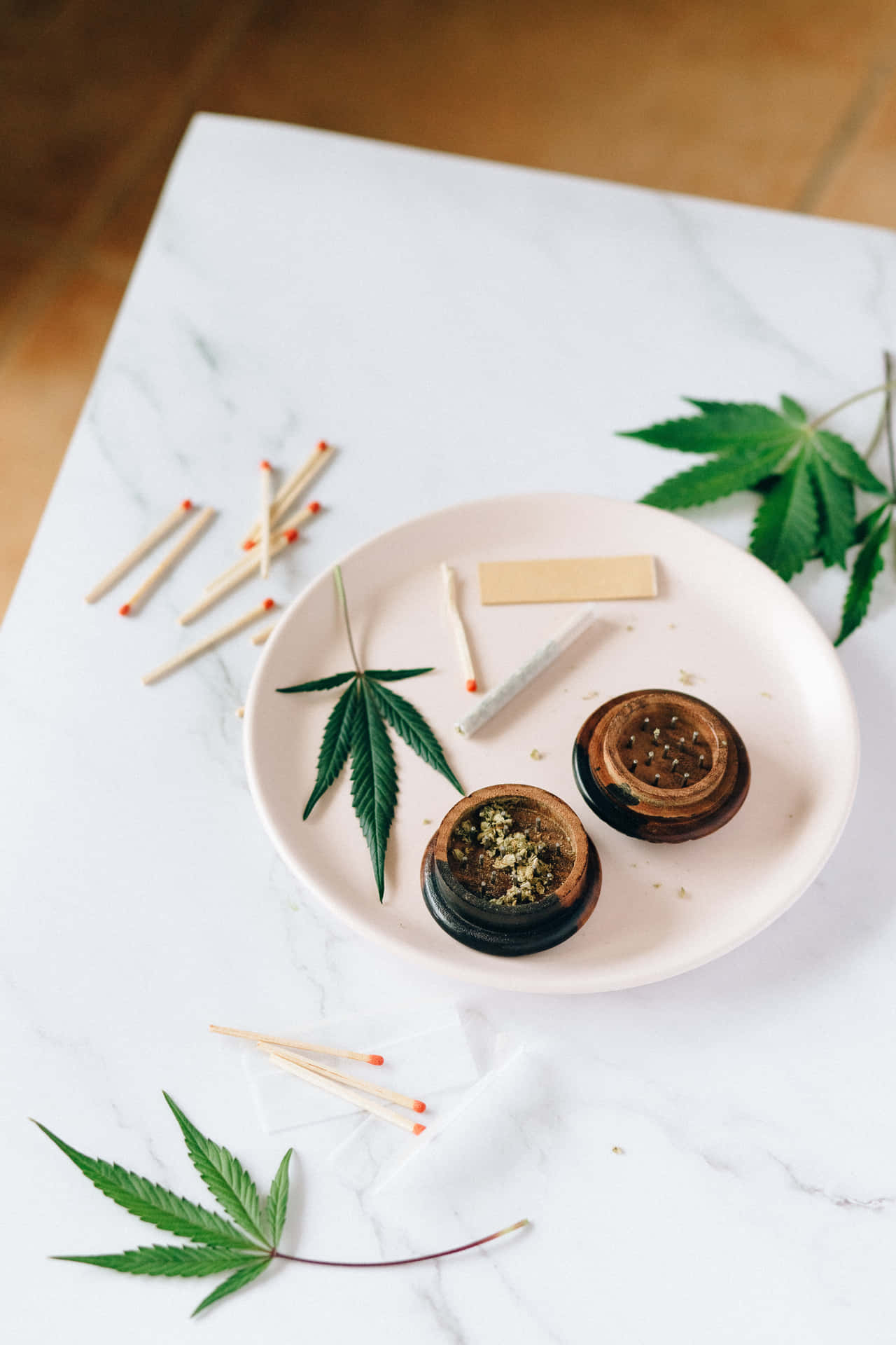 大麻研磨器和捲紙，配以新鮮樹葉和火柴，置於大理石上。