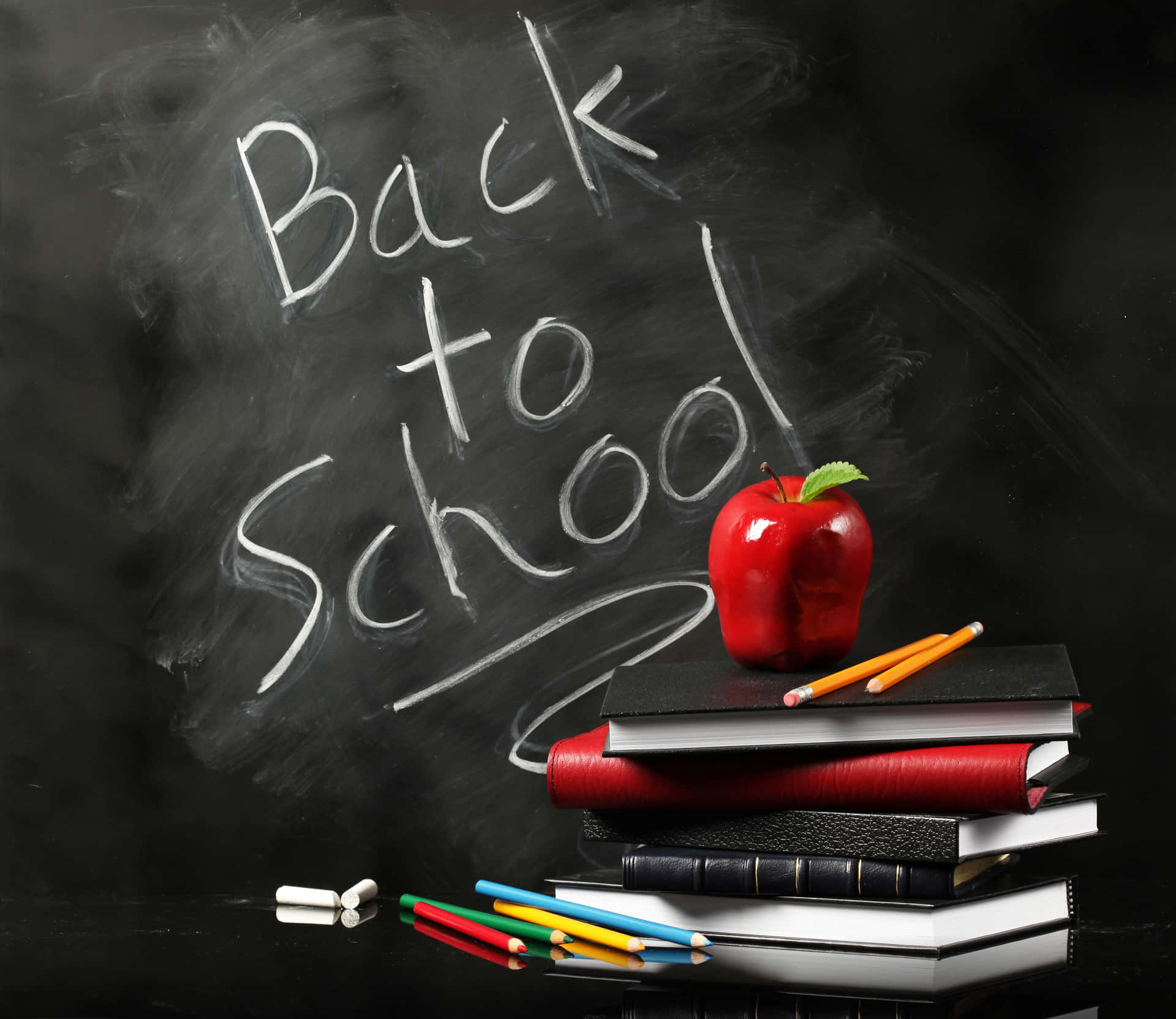 書本上的紅蘋果，旁邊有粉筆寫的「Back to School」。