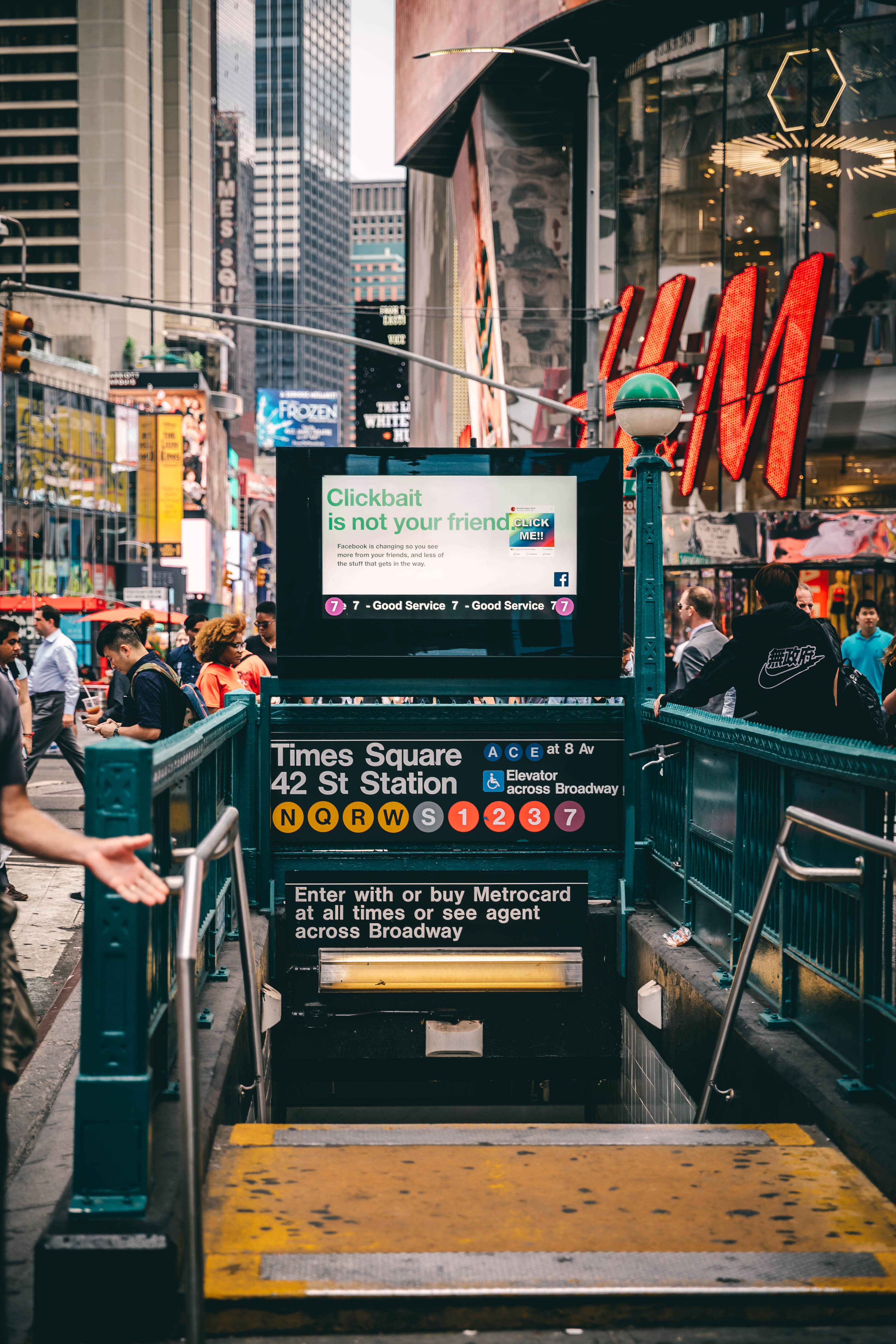 時代廣場42街地鐵站階梯 壁紙 — 白天時代廣場地鐵入口，人潮湧動，廣告牌明亮，摩天大樓高聳入雲。
