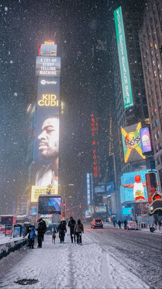 夜晚積雪的時報廣場，閃爍的廣告牌和行走的行人。