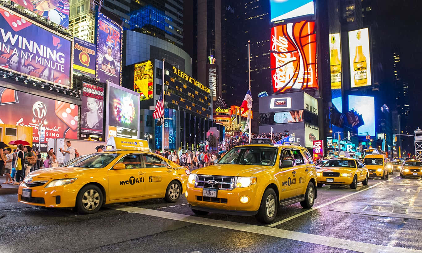 Yellow Cab 桌布 壁紙 — 時代廣場充滿活力的夜景，黃色的士和耀眼的數碼廣告牌照亮了繁華的城市街道。