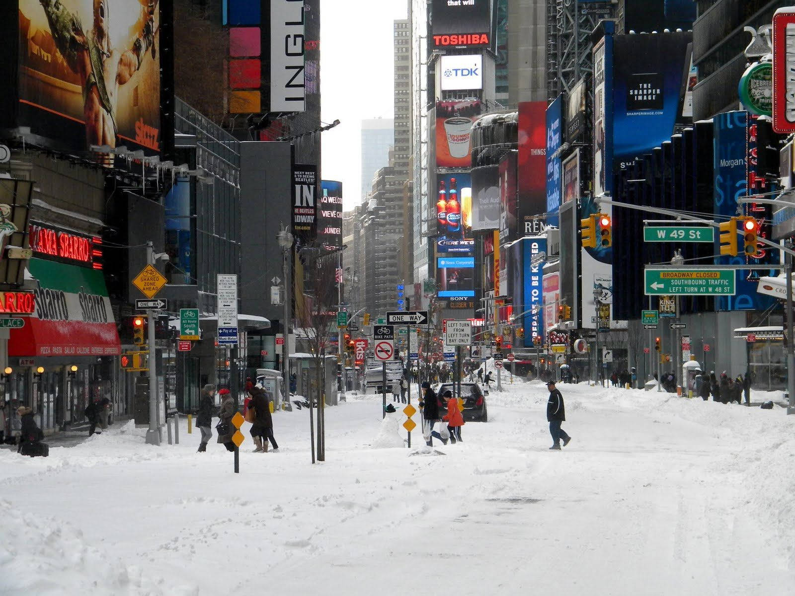 時代廣場被白雪覆蓋，行人在高聳建築物之間行走。