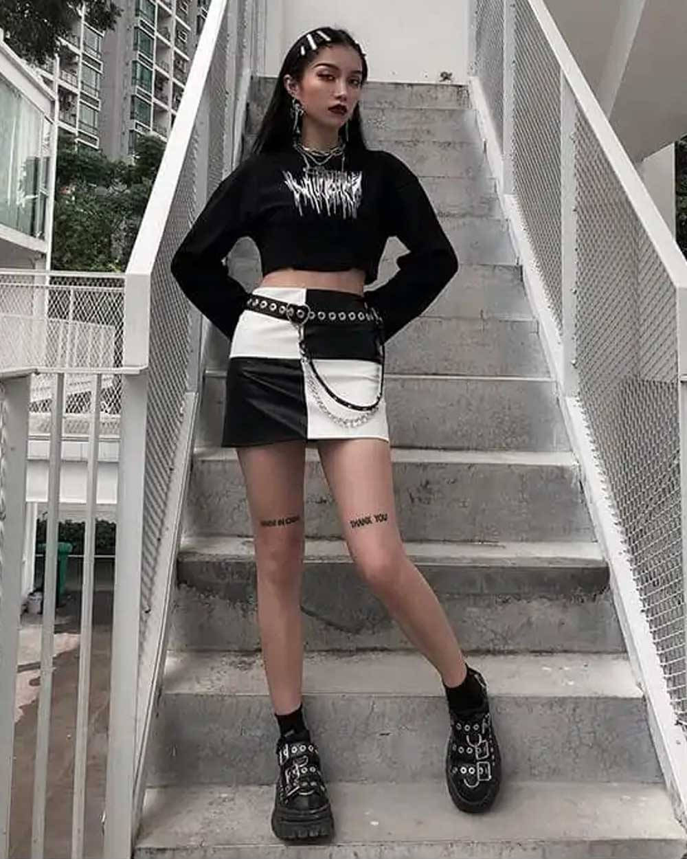 穿著龐克街頭服的年輕女性在混凝土樓梯上擺姿勢。