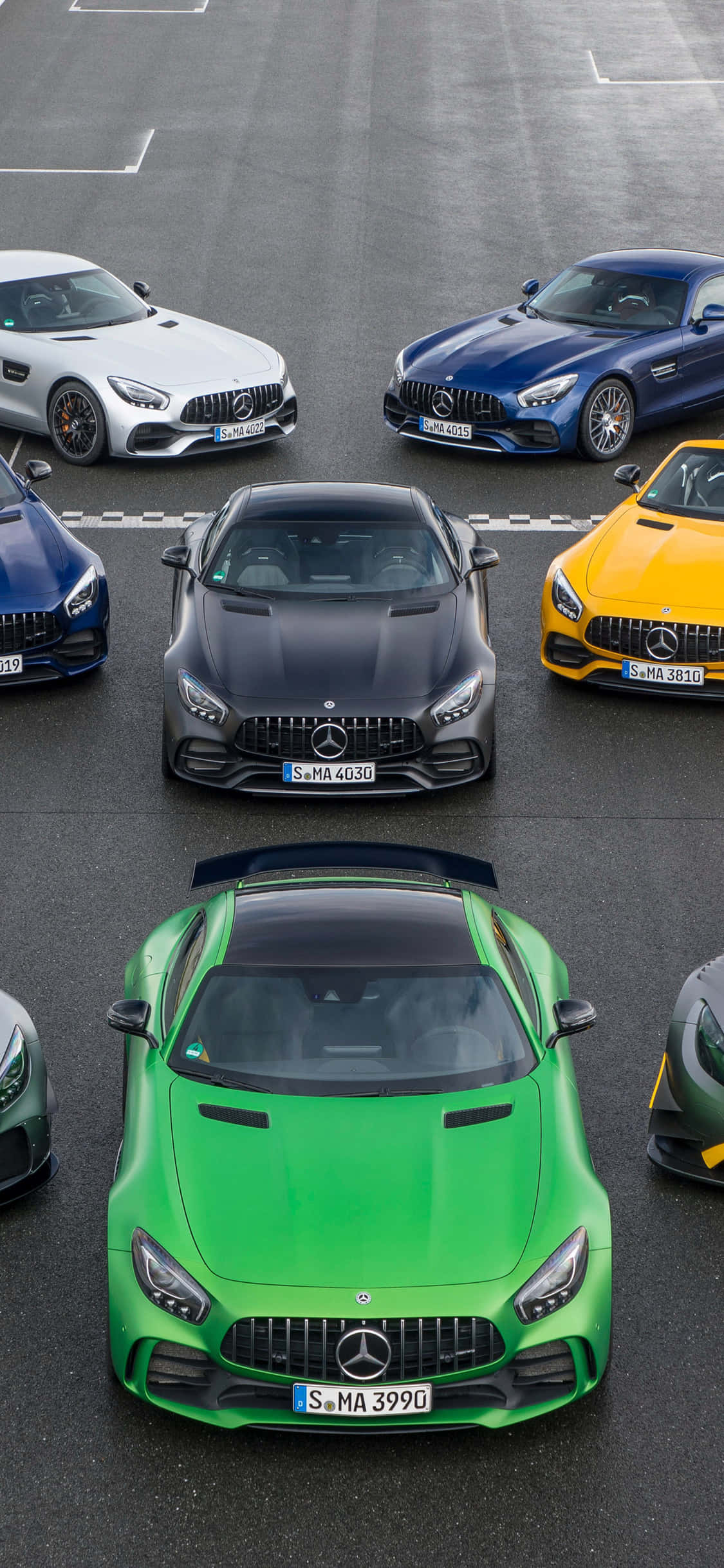 時尚 iPhone X 壁紙，展現 AMG GT-R 的速度與美學 壁紙 — 從上方俯瞰六輛高性能 Mercedes-AMG GT 跑車以網格形式停泊在灰色瀝青場地上。