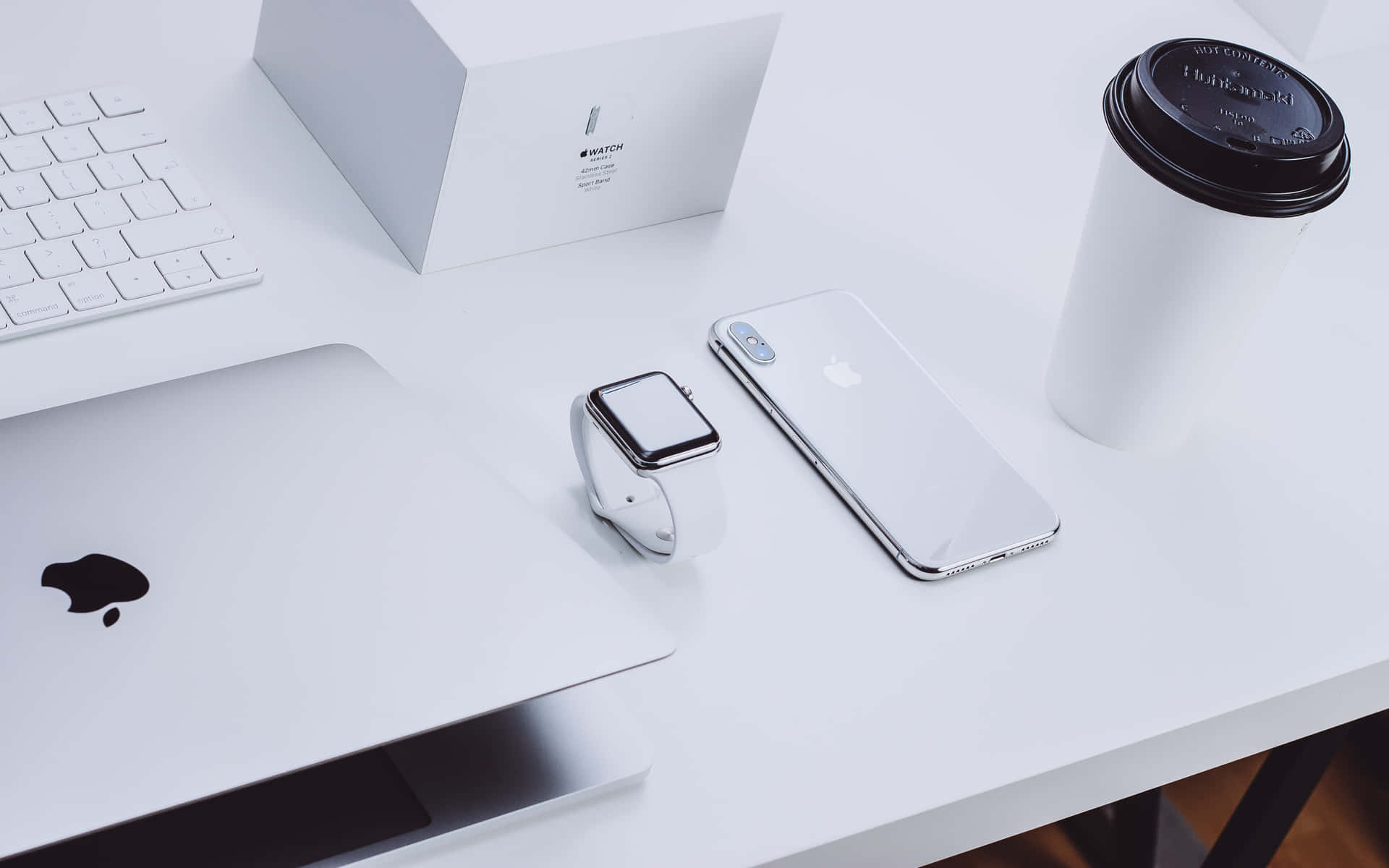 乾淨現代桌面，配備Apple手提電腦、手錶、電話和咖啡杯。
