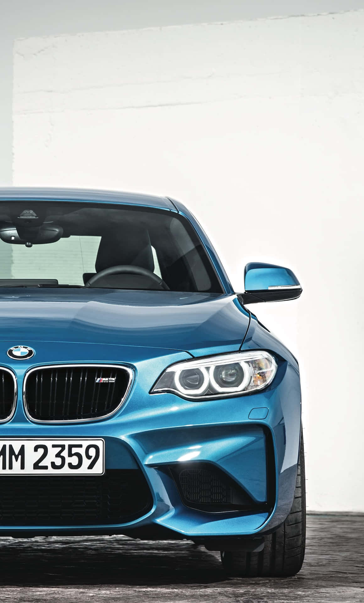 在攝影棚環境中，藍色BMW M2跑車配備銳利頭燈和黑色格柵。