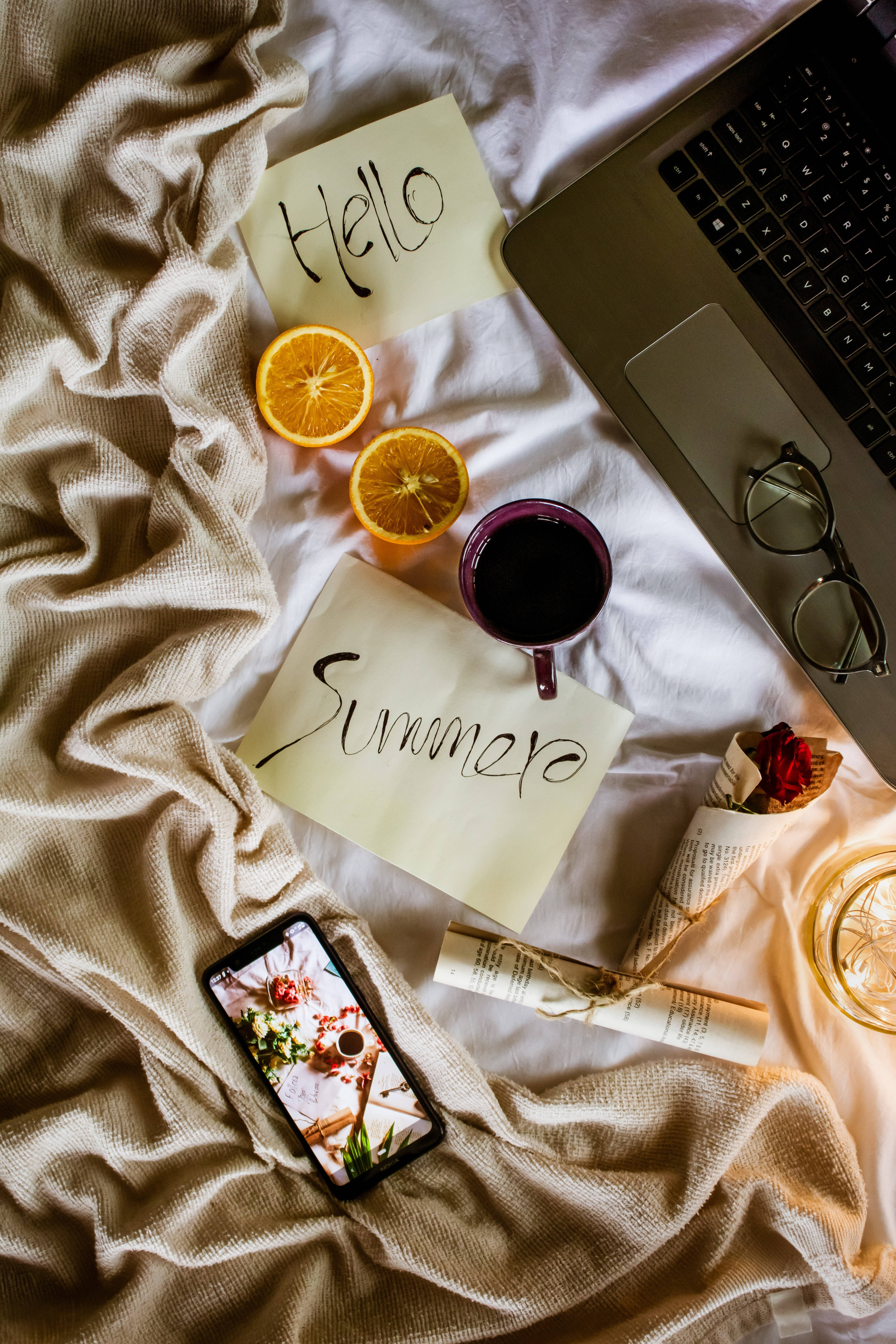 時尚Tumblr筆記本電腦與咖啡杯床平鋪 壁紙 — 一張床的舒適俯視圖，上面有手提電腦、眼鏡、橙片、咖啡和手寫筆記，歡迎夏天的到來。