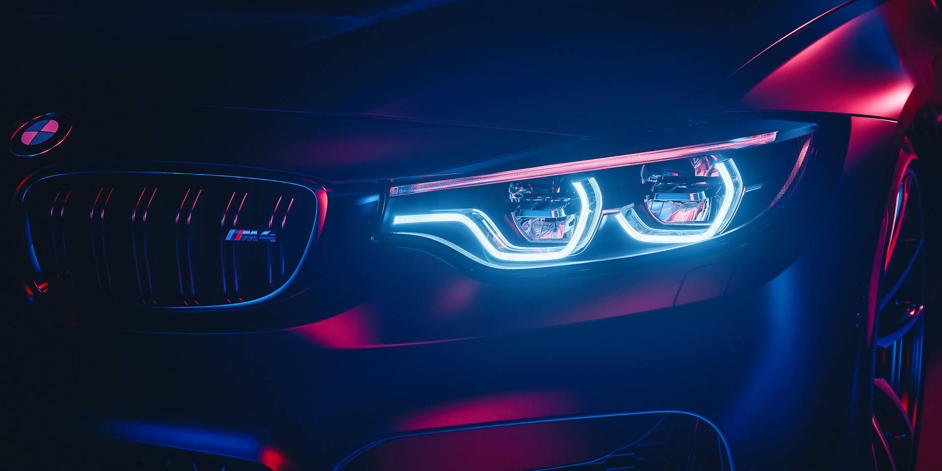 BMW M4 正面，在黑暗環境中帶有發光的藍色和洋紅色車頭燈