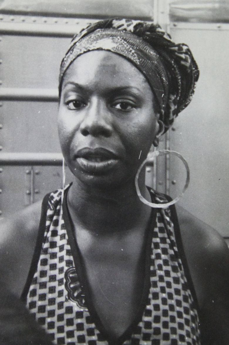 時尚偶像 Nina Simone 大耳環造型 壁紙 — 一個引人注目的黑白肖像，一位戴著大圈耳環和圖案頭巾的女性直視鏡頭。