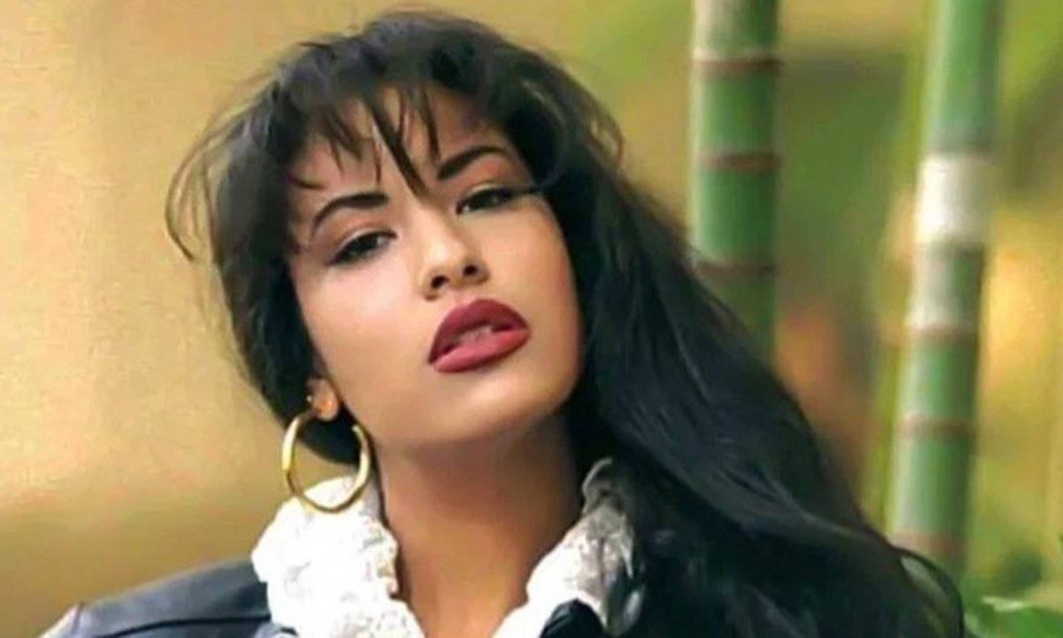 時尚偶像 Selena Quintanilla 壁紙 — 一位深色頭髮、大膽紅唇的女性在綠色竹莖背景下向上凝視。