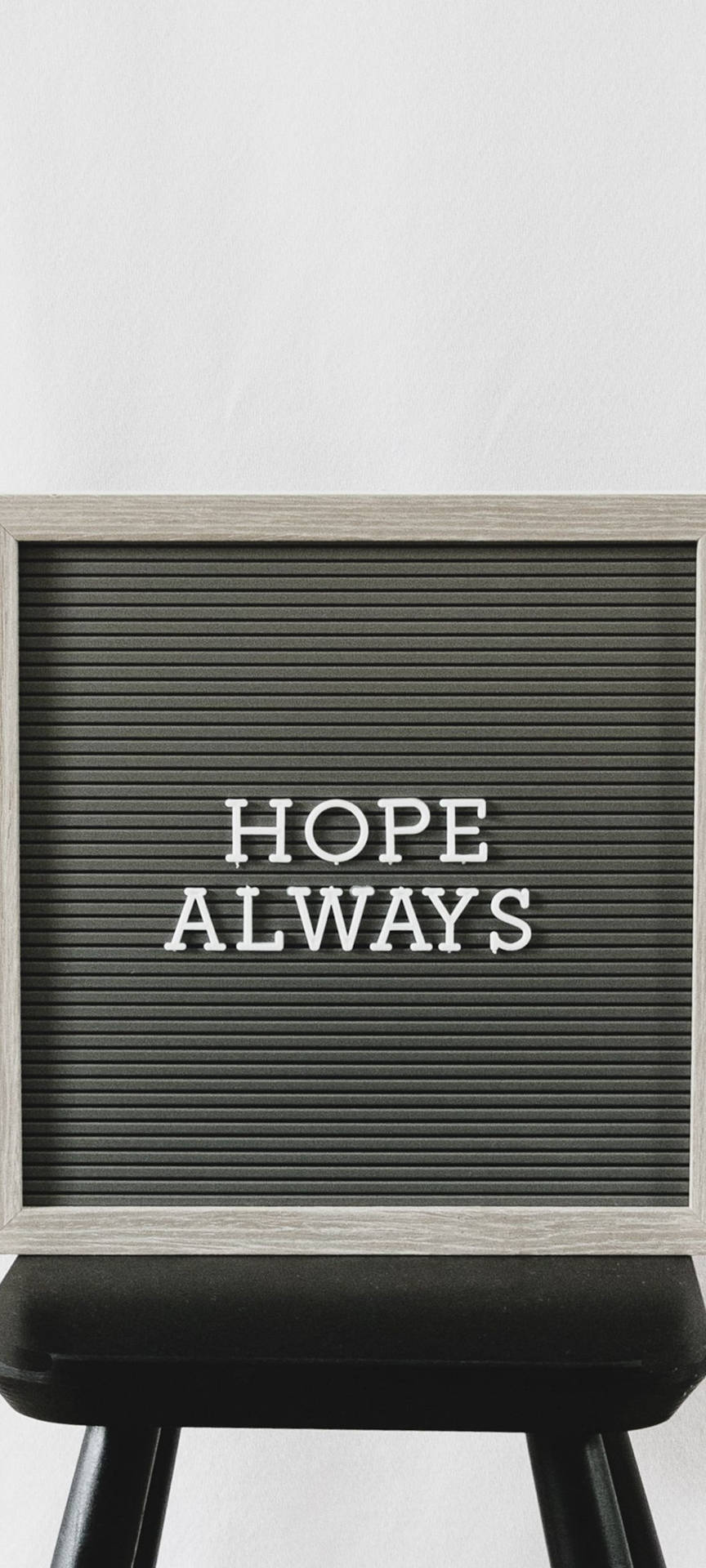 一個黑色字母板，上面用白色字母寫著HOPE ALWAYS，放在一個黑色凳子上。