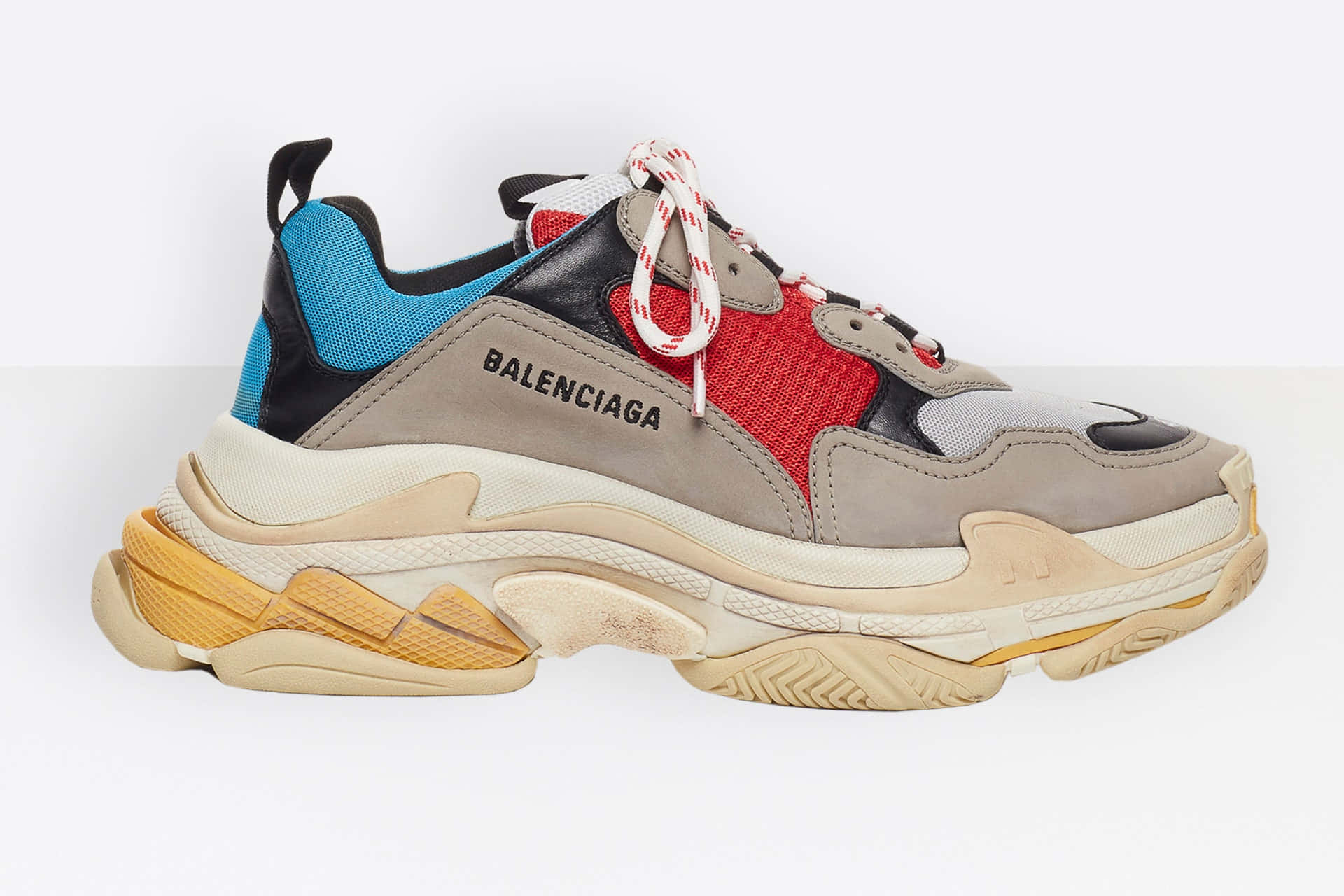 時尚出街，展現Balenciaga風格 壁紙 — 一雙大膽的Balenciaga運動鞋，配以厚實的分層鞋底，以及鮮豔的紅色、藍色和米色面板，置於純白背景上。