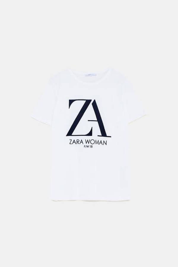 時尚前衛的ZARA 壁紙 — 一件純白T恤，上面印有醒目的黑色ZARA WOMAN F/W 18標誌，背景為簡潔的淺色背景。