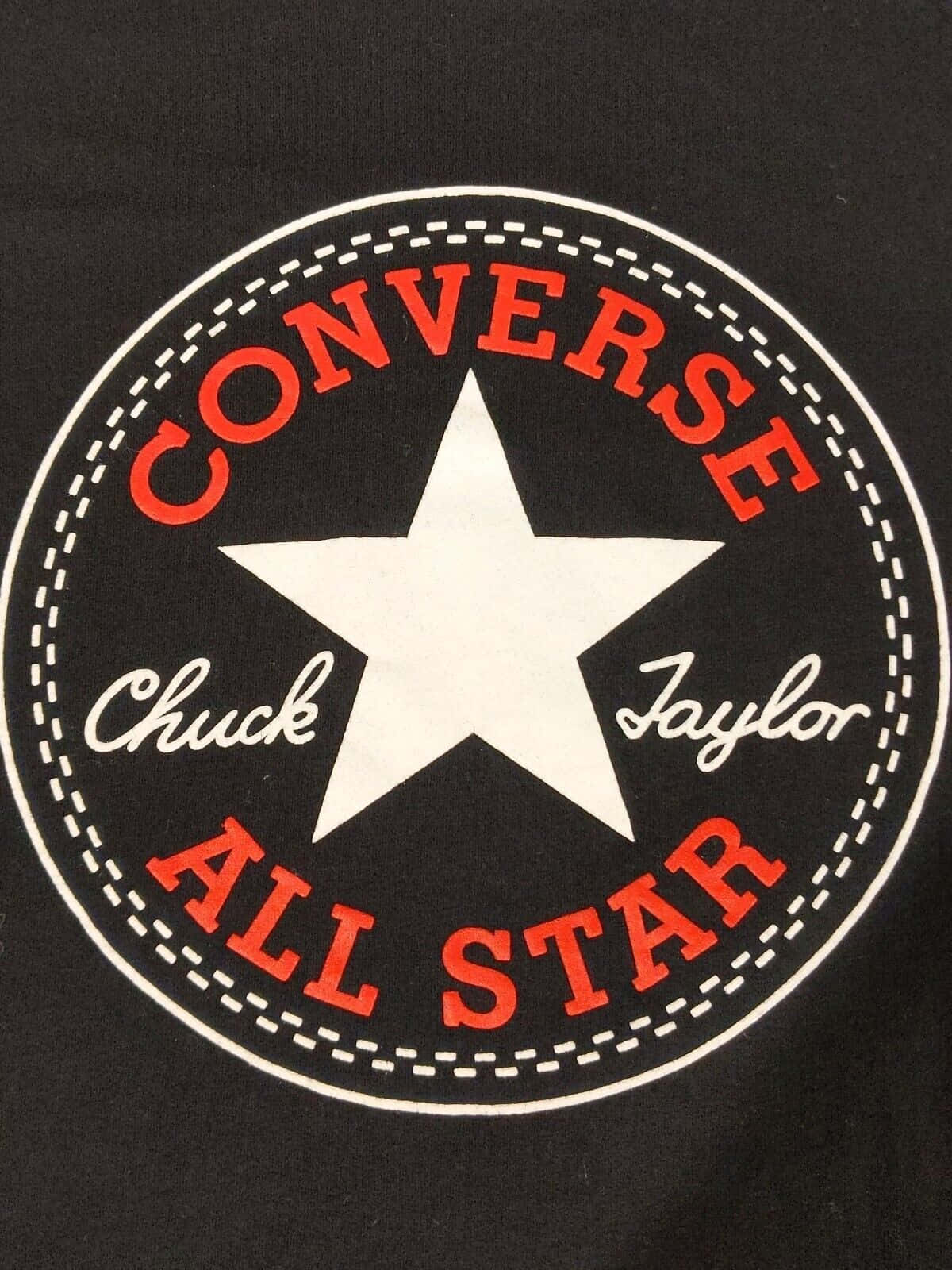 時尚匡威鞋履 壁紙 — 黑色T恤特寫，帶有標誌性的紅白Converse Chuck Taylor All Star標誌，並有縫線圓形設計。