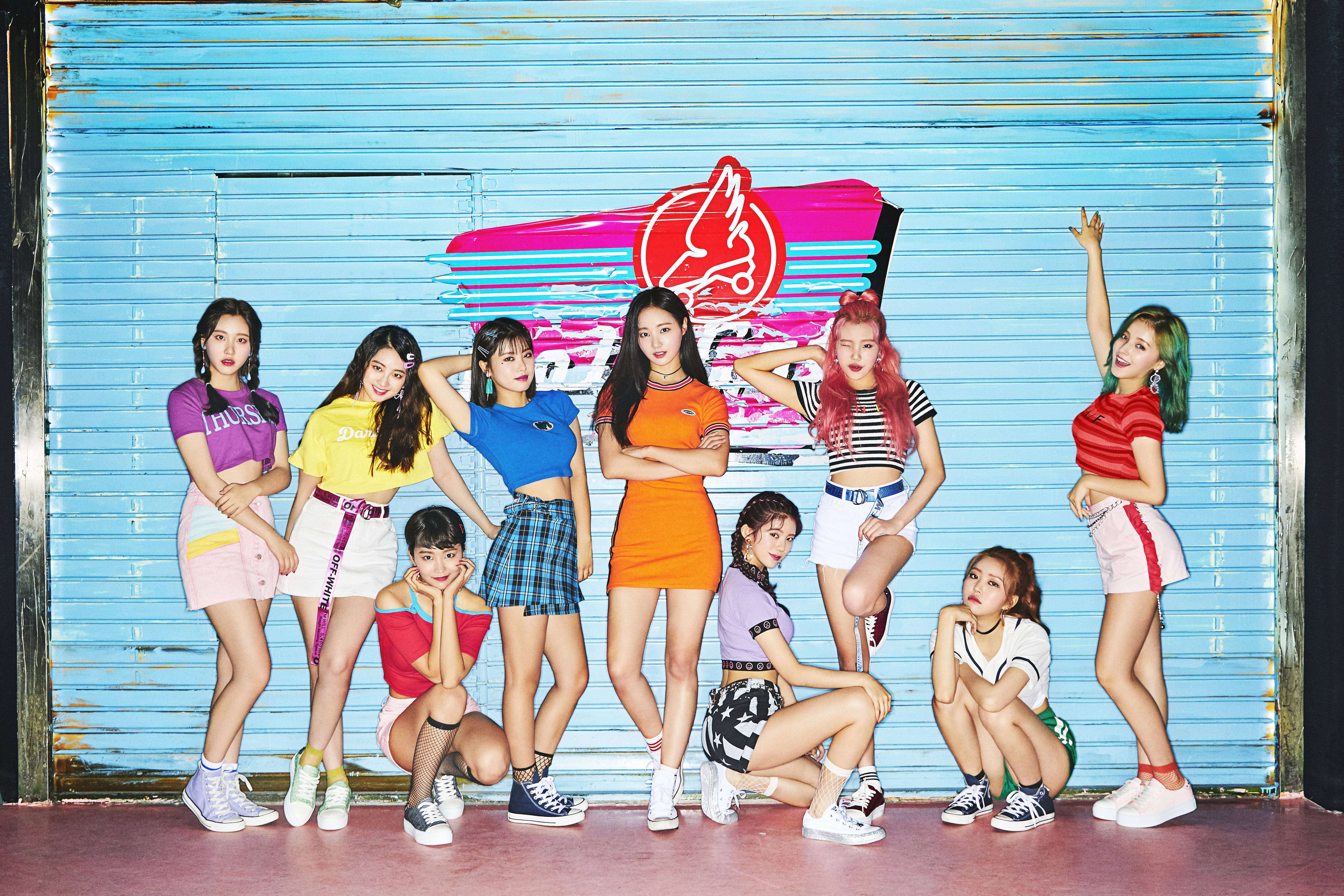 時尚南西 Momoland 高畫質壁紙 壁紙 — 七位時尚年輕女性身穿鮮豔復古服裝，在藍色波紋金屬牆前自信擺姿勢，牆上有粉紅色霓虹標誌。