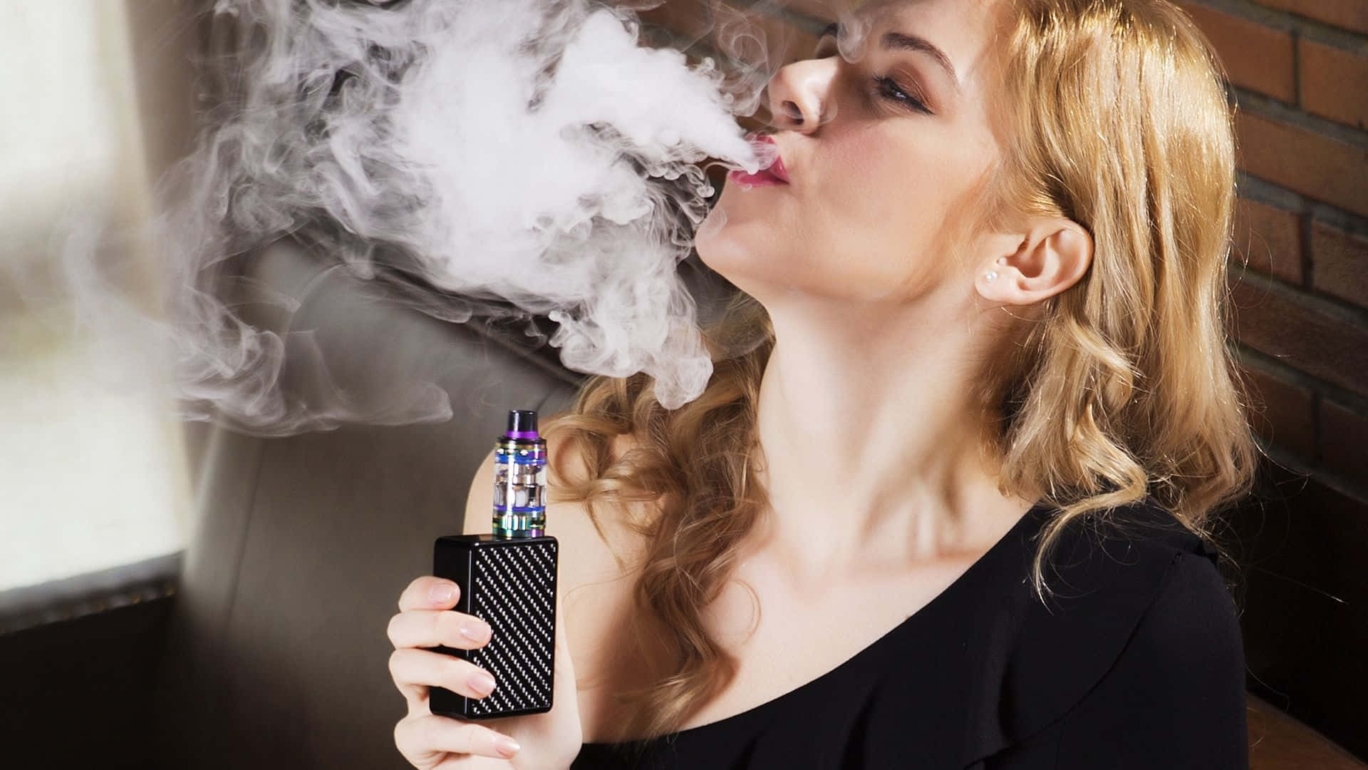 時尚地抽菸 壁紙 — 一位金髮女性在磚牆背景下呼出一團濃厚的蒸氣，同時手持電子煙裝置。