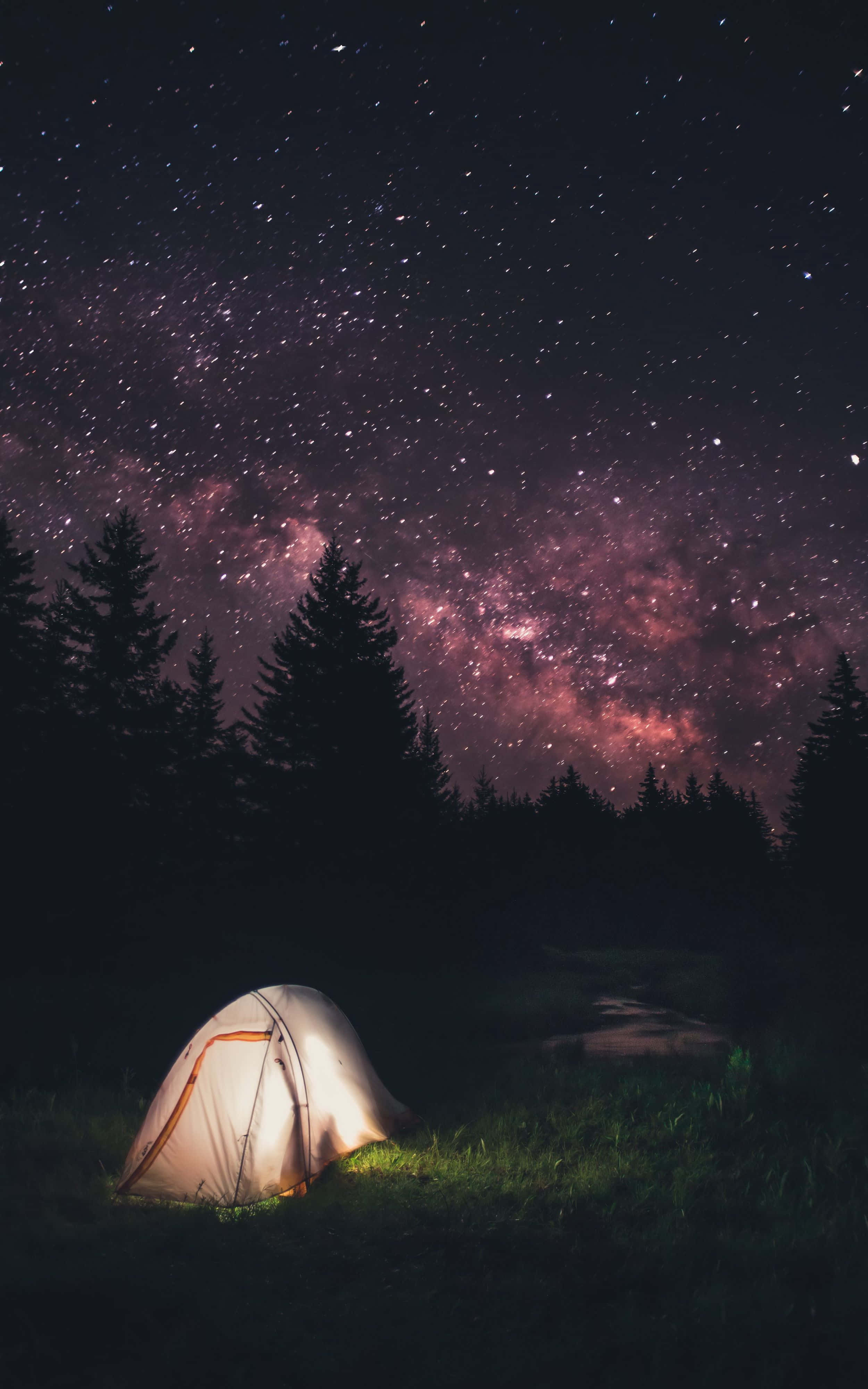 時尚幾何智慧手機背景 壁紙 — 一個發光的帳篷坐落在草地上，上方是充滿活力的紫色和粉紅色星空，銀河拱形橫跨天際。