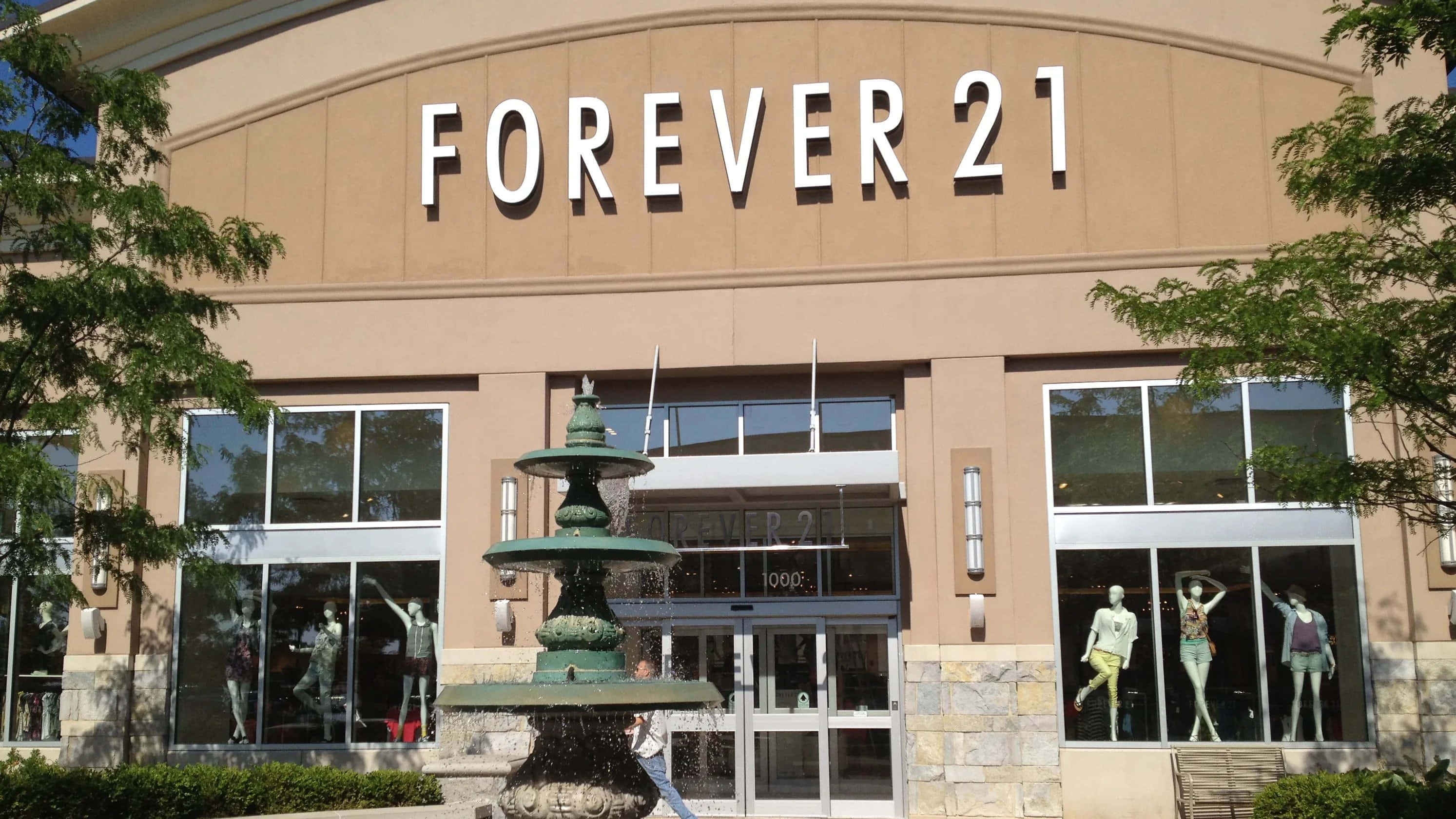時尚有型，舒適自在 — Forever 21 壁紙 — Forever 21 店舖外觀的晴朗日間照片，前面有綠色噴泉，櫥窗內有模特兒。