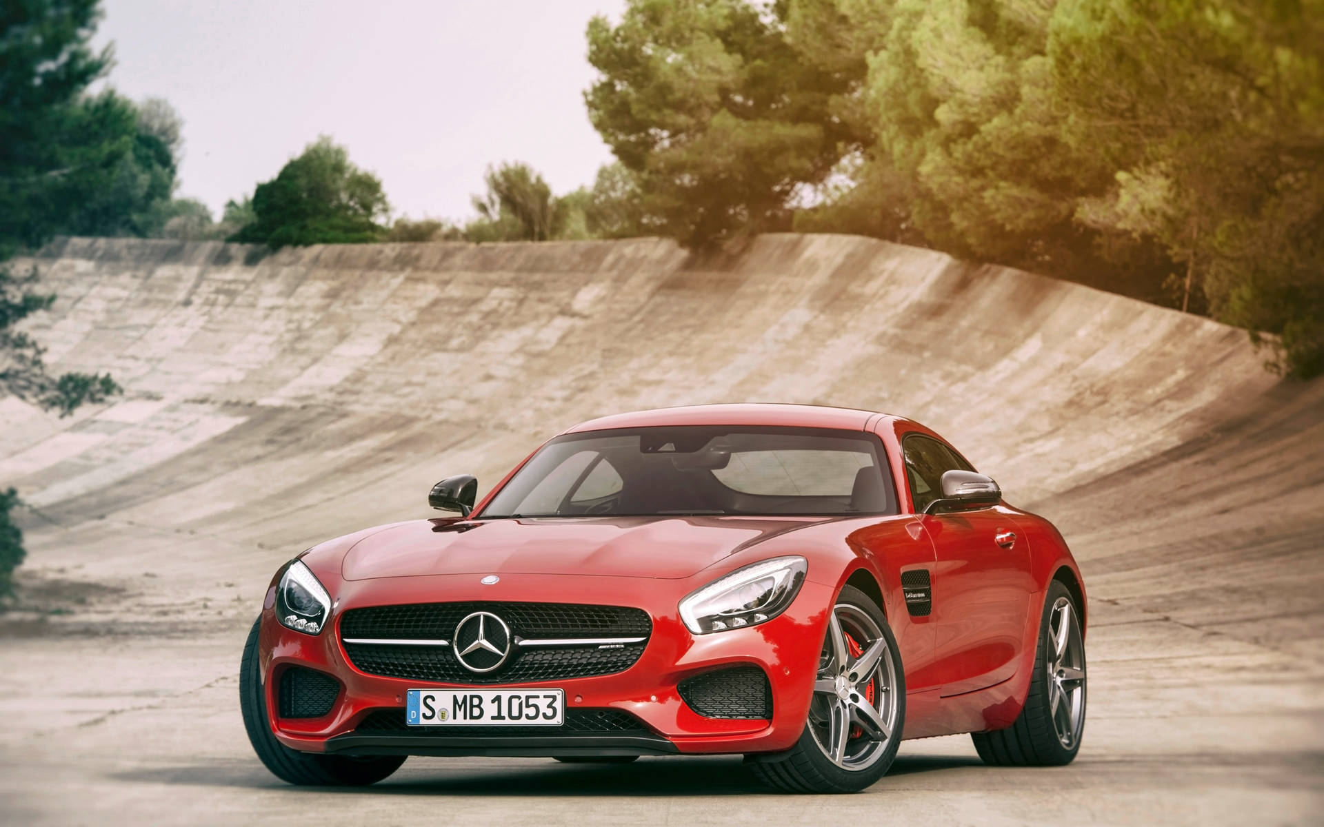 紅色 Mercedes-AMG GT 跑車停在彎曲的混凝土坡道上，背景有樹木。