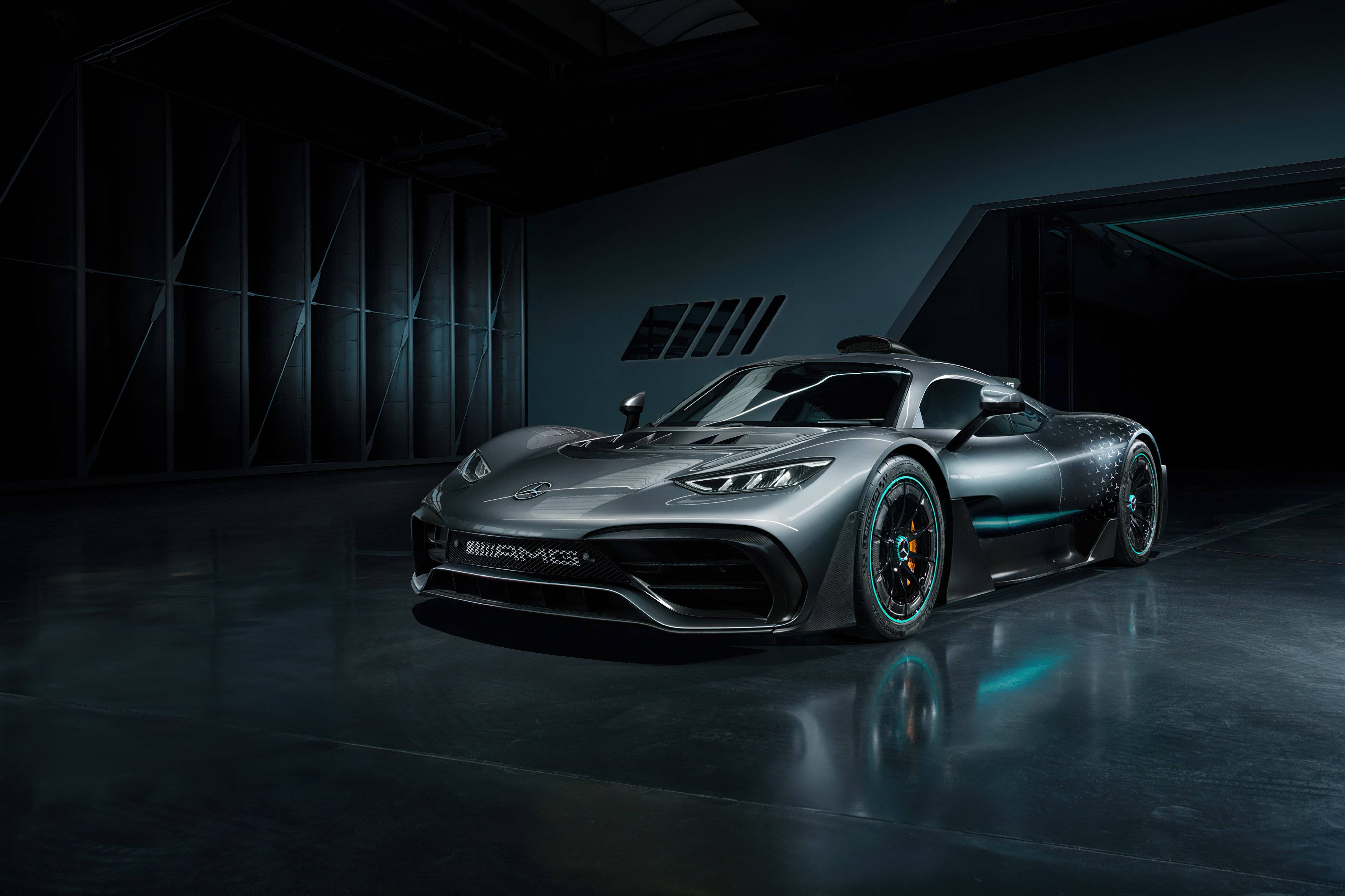 時尚灰AMG停泊現代車庫 壁紙 — 一輛時尚的銀色 Mercedes-AMG One 超跑在昏暗的工業車庫中，在戲劇性的燈光下閃閃發光。