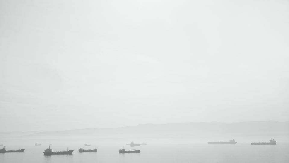 霧港有貨船同遠處山丘，灰色天空