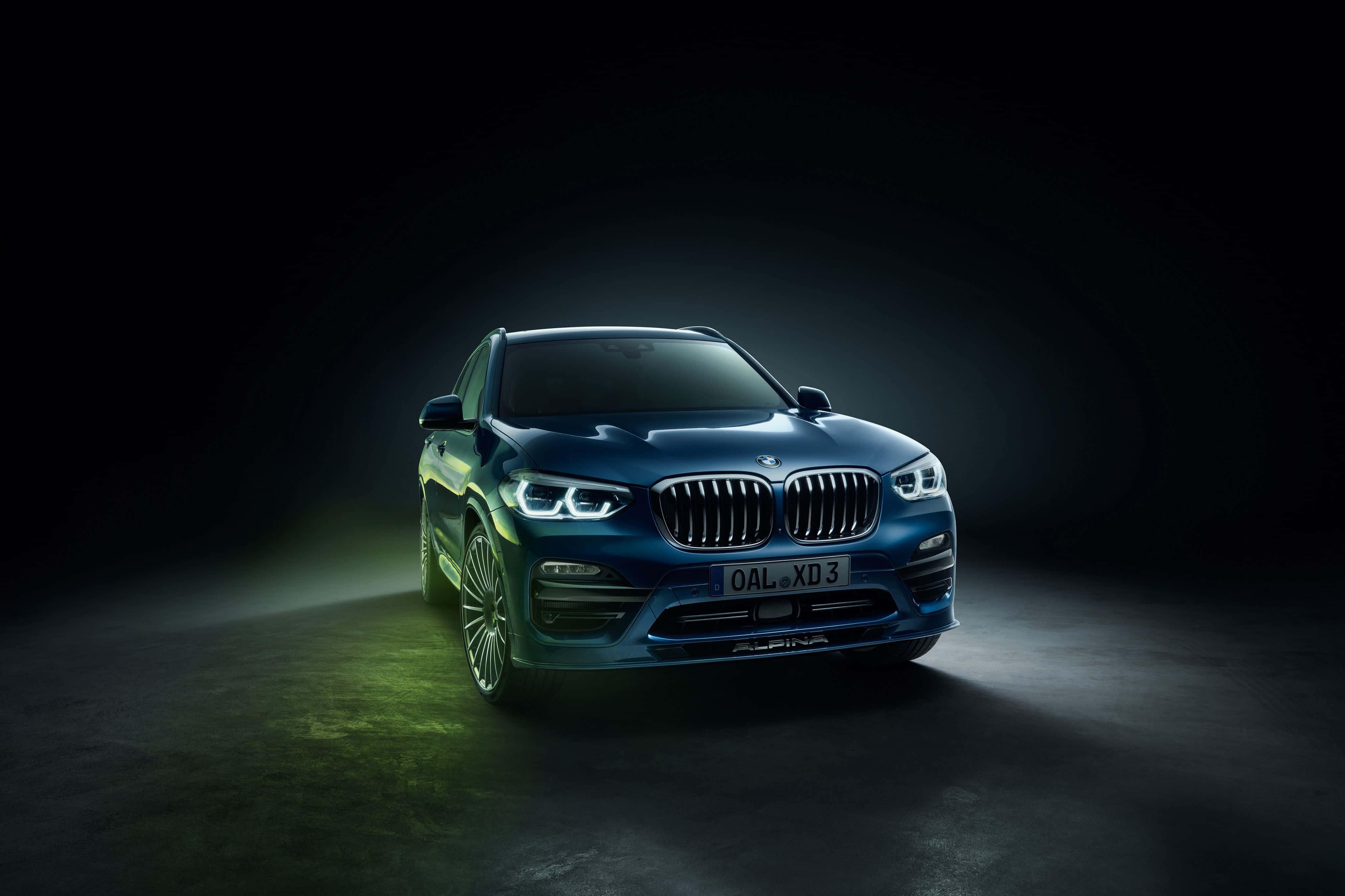 Bmw X3 桌布 壁紙 — 時尚的藍色BMW X5 Alpina在黑暗的攝影棚背景下，配合綠色地板光芒，在戲劇性的聚光燈下閃耀。