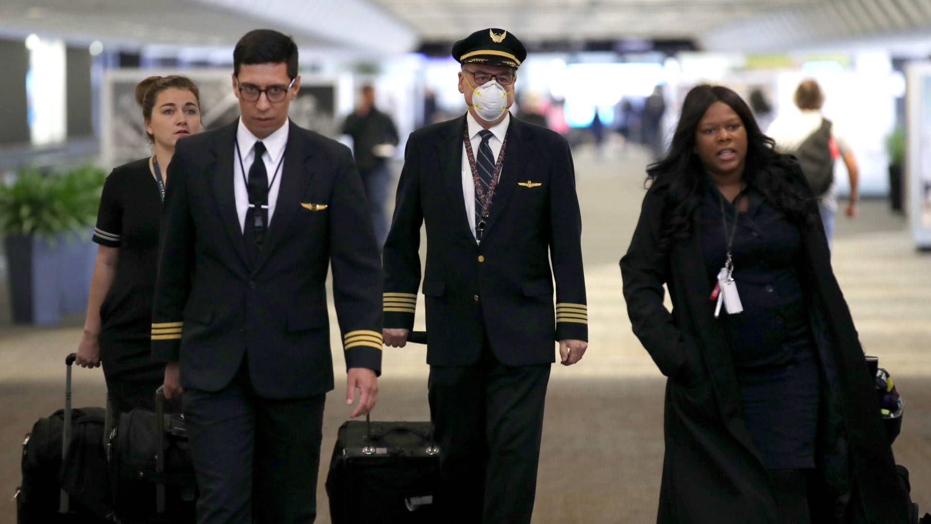穿著制服的航空公司機組人員帶著行李走過機場航站樓。