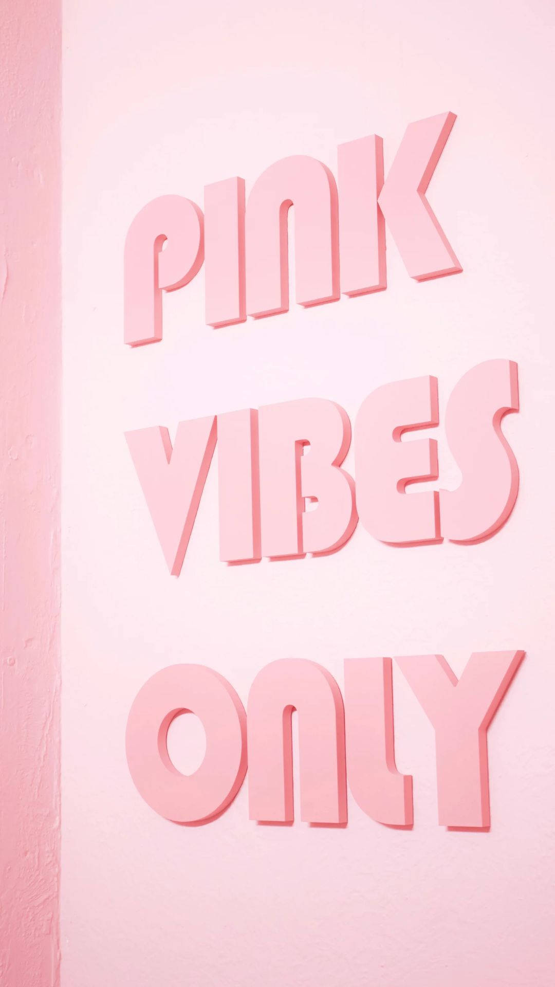 粉紅色 3D 字母在粉紅色牆上顯示 'PINK VIBES ONLY'。