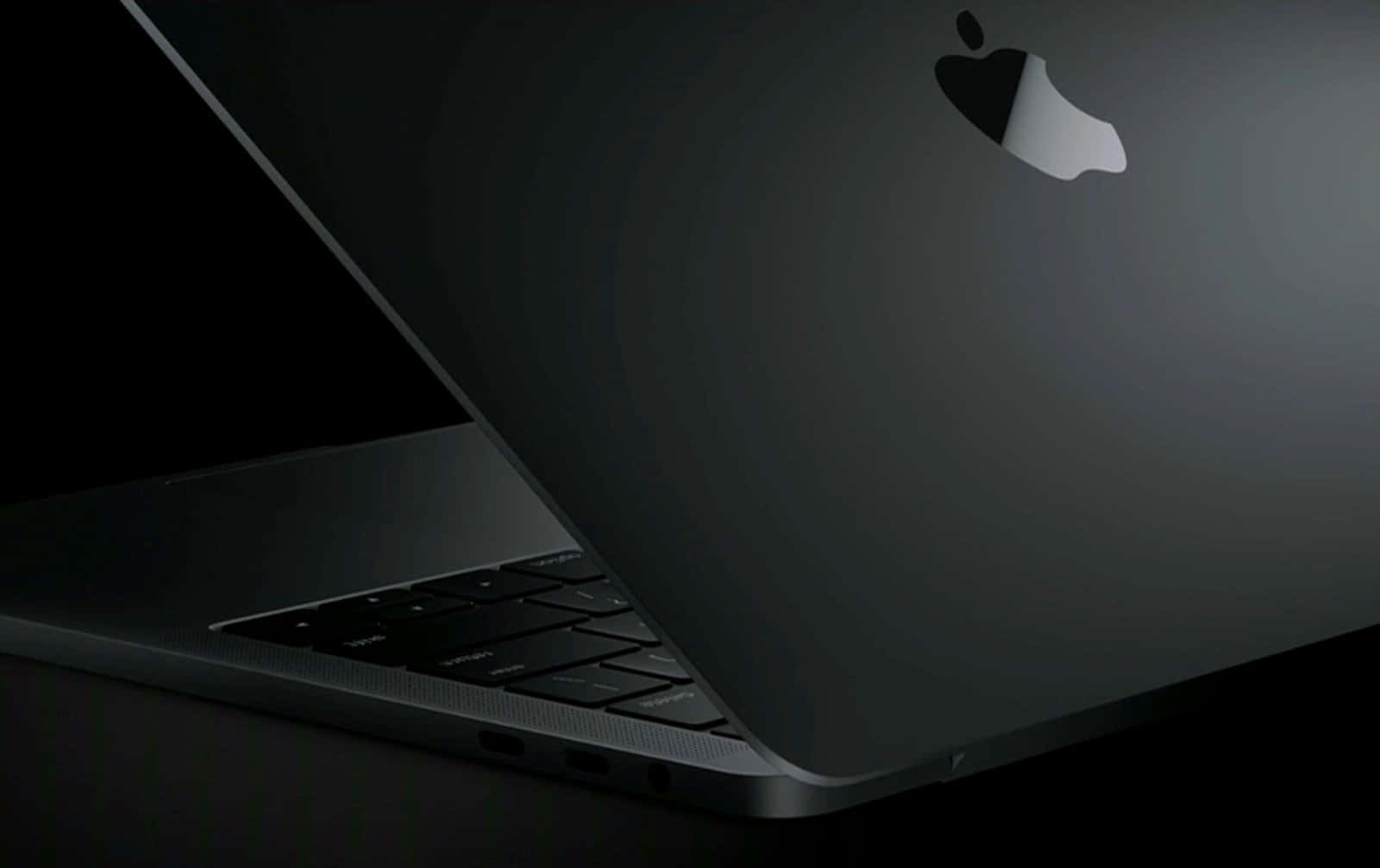 黑色MacBook手提電腦的特寫，帶有在昏暗光線下發光的Apple標誌。
