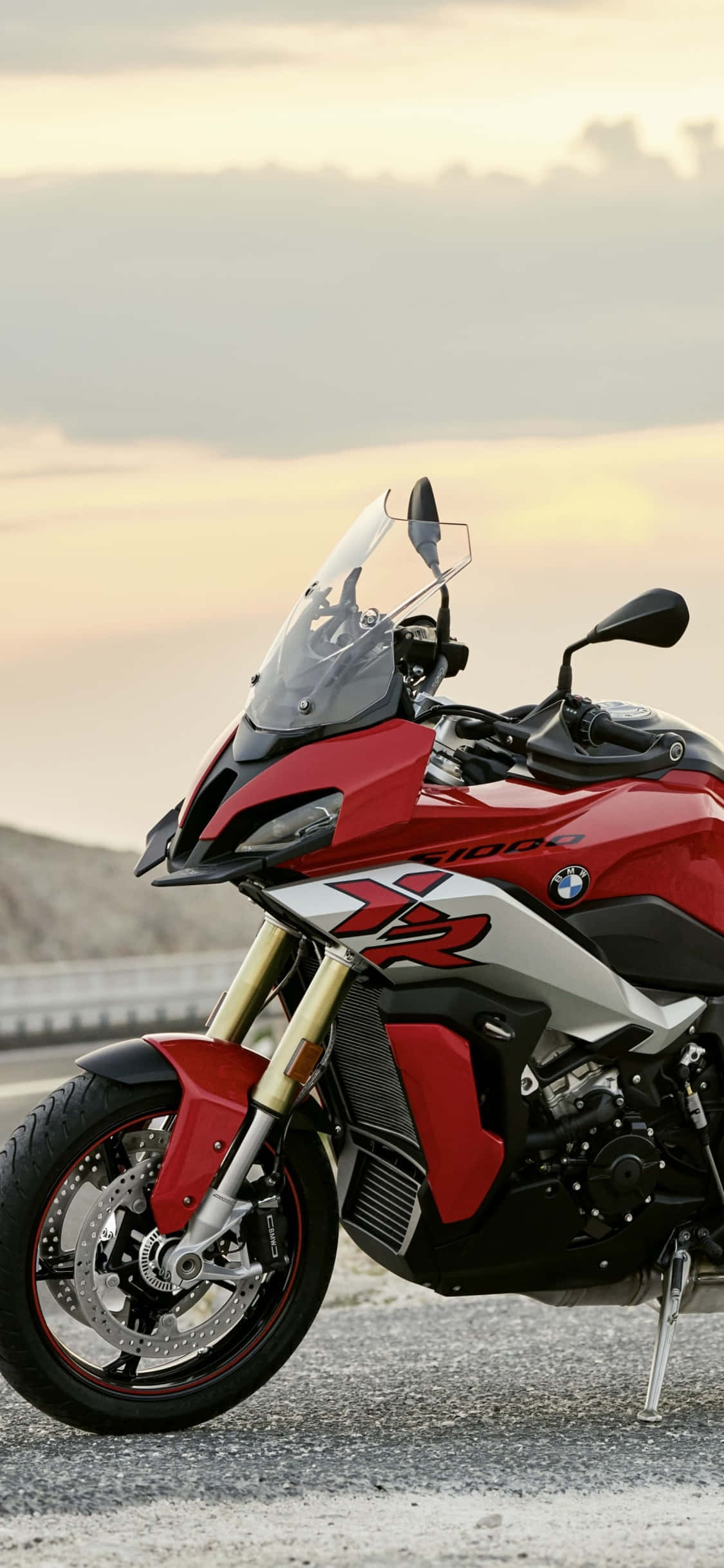 時尚與奢華的完美結合 壁紙 — 一輛紅色BMW R 1200 GS冒險電單車停在碎石路邊，背景是柔和的金色日落天空。