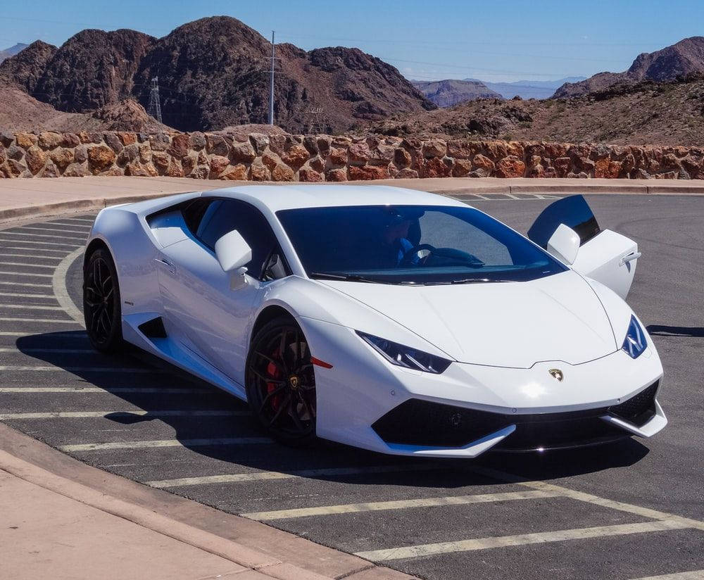 白色林寶堅尼 Huracán 停泊在沙漠停車場，背後有山脈。