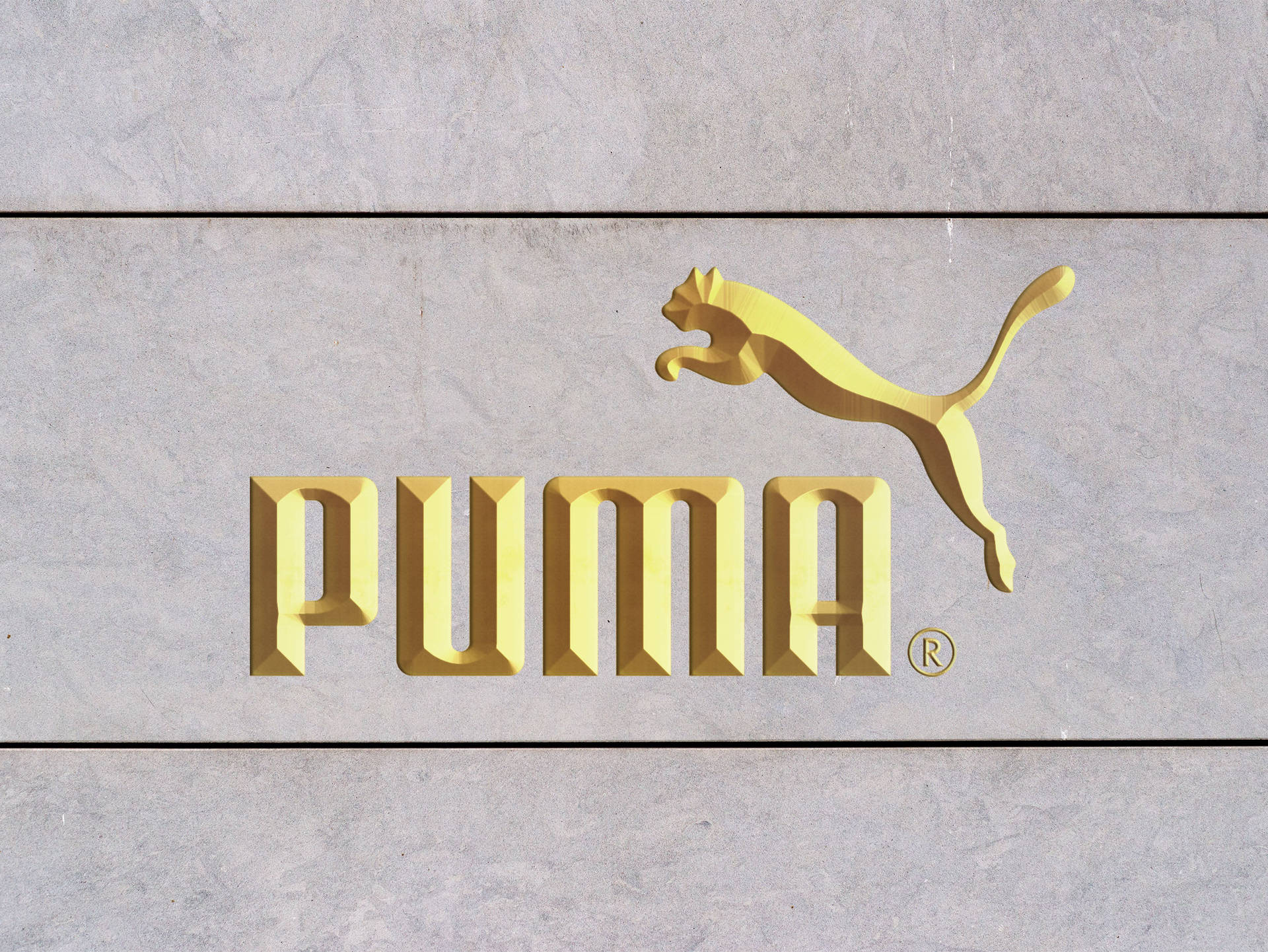 灰色石牆上的金色Puma品牌標誌