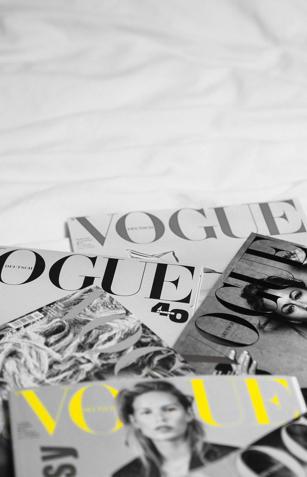 Vogue雜誌散落在白色床單上，其中一本黃色封面。