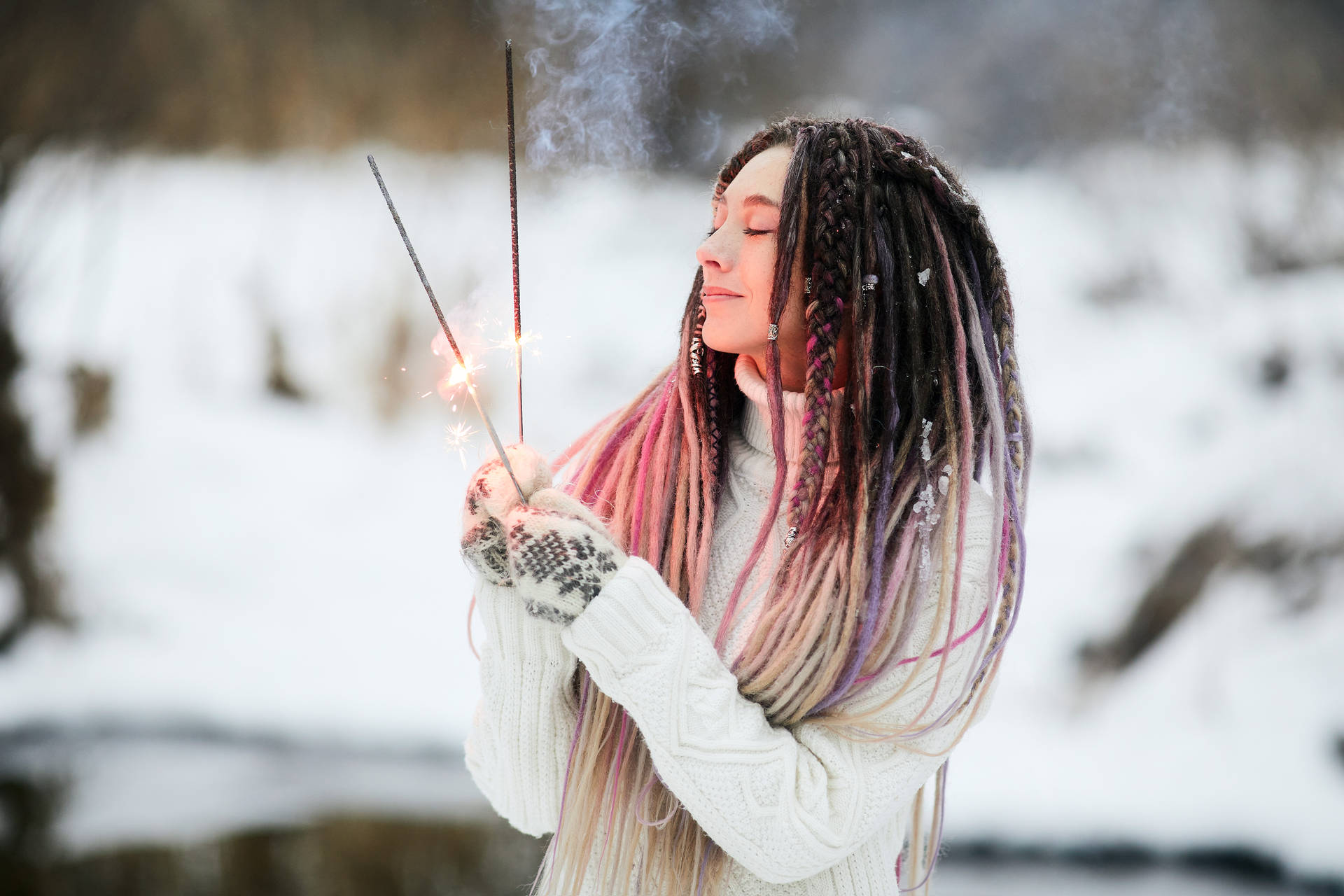 擁有彩色辮子的女性在雪地冬季環境中手持煙花